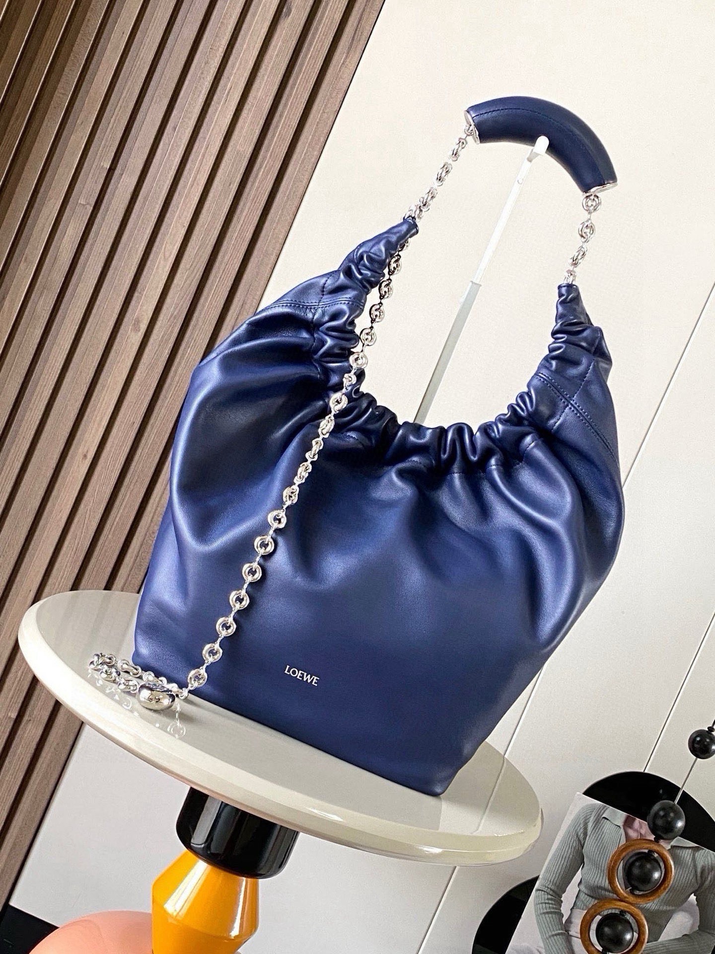NO:880431,[Celebrity Style] Medium Nappa Lamb Leather Squeeze Handbag is a refined and feminine new handbag. The newly released Squeeze Handbag is made of soft and silky Mellow Nappa lambskin. The unlined structure effectively reduces the weight of the bag and makes it lighter in appearance. The crescent-shaped bag mouth is closed with elegant ruffles, creating a relaxed and casual attitude. Another highlight of this bag is the ergonomic Squeeze  The airbag handle is paired with a delicate donut chain made of brass. The length can be adjusted through the chain link or an extension chain can be added to realize different carrying methods such as hand carry, shoulder carry, crossbody, etc. The airbag handle can slide freely to improve comfort. An Anagram Pebble pendant is embellished at the bottom of the chain to add smart details to the bag. Size 34CM～33CM～13.5CM Style No. 9041 Color Navy blue, Loewe, loewe, sheepskin19860909【明星同款】中号纳帕羊皮革Squeeze手袋是款精致而柔美的全新手袋全新发布的 Squeeze 手袋采用柔软丝滑的Mellow纳帕小羊皮制作而成无衬里结构有效减轻包身自重观感上也更为轻盈弯月形包口以优雅的褶边收口,营造出轻松又随性的态度这款包包还有一大亮点是符合人体工程学的 Squeeze 气囊手柄搭配黄铜打造的精美甜甜圈链条可通过链环调节长短或添加延长链,实现手拎、肩背、斜挎等不同背法气囊手柄可自由滑动位置以提升舒适度链条底部点缀一枚 Anagram Pebble 吊坠,为包包增添灵动细节 尺寸34CM～33CM～13.5CM 款号9041 颜色海军蓝,罗意威,loewe,sheepskin,Bag