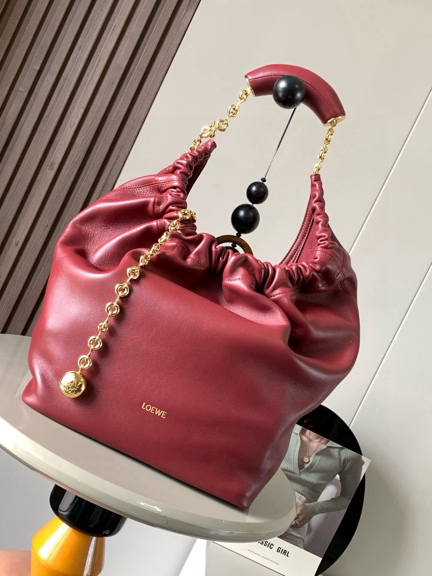 NO:880435,[Celebrity Style] Medium Nappa Lamb Leather Squeeze Handbag is a refined and feminine new handbag. The newly released Squeeze Handbag is made of soft and silky Mellow Nappa lambskin. The unlined structure effectively reduces the weight of the bag and makes it lighter in appearance. The crescent-shaped bag mouth is closed with elegant ruffles, creating a relaxed and casual attitude. Another highlight of this bag is the ergonomic Squeeze  The airbag handle is matched with a delicate donut chain made of brass. The length can be adjusted through the chain link or an extension chain can be added to realize different carrying methods such as hand carry, shoulder carry, crossbody, etc. The airbag handle can slide freely to improve comfort. An Anagram Pebble pendant is embellished at the bottom of the chain to add smart details to the bag. Size 34CM～33CM～13.5CM Style No. 9041 Color: Burgundy Red, Loewe, Loewe, Sheepskin19860909【明星同款】中号纳帕羊皮革Squeeze手袋是款精致而柔美的全新手袋全新发布的 Squeeze 手袋采用柔软丝滑的Mellow纳帕小羊皮制作而成无衬里结构有效减轻包身自重观感上也更为轻盈弯月形包口以优雅的褶边收口,营造出轻松又随性的态度这款包包还有一大亮点是符合人体工程学的 Squeeze 气囊手柄搭配黄铜打造的精美甜甜圈链条可通过链环调节长短或添加延长链,实现手拎、肩背、斜挎等不同背法气囊手柄可自由滑动位置以提升舒适度链条底部点缀一枚 Anagram Pebble 吊坠,为包包增添灵动细节 尺寸34CM～33CM～13.5CM 款号9041 颜色勃良地红,罗意威,loewe,sheepskin,Bag