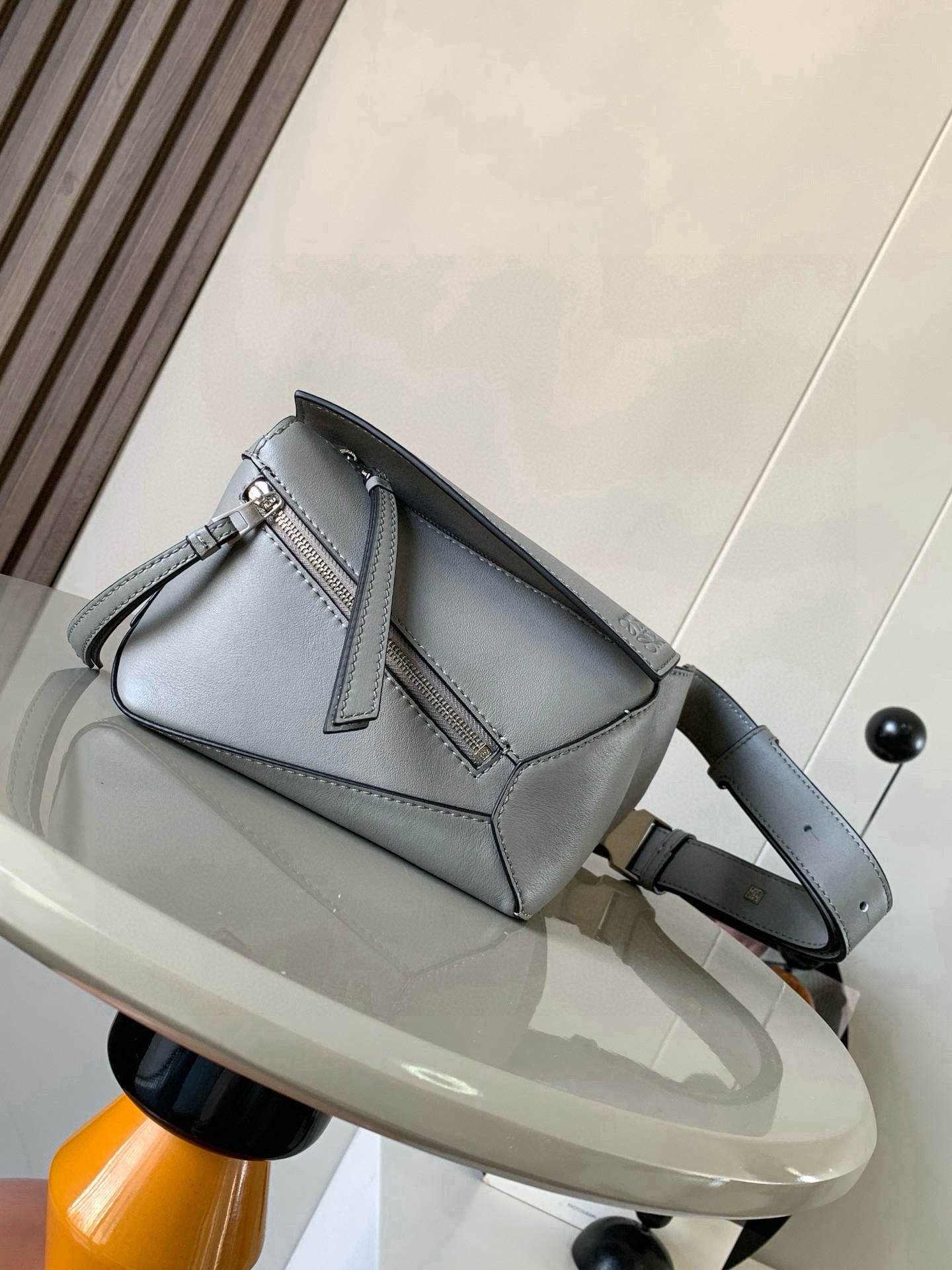 NO:880505,The new mini classic cow leather Puzzle waist bag has a rectangular shape and precise cutting technology to create Puzzle's unique geometric lines. This small mini waist bag is made of classic cow leather. The leather is soft and lightweight, and the shape is low-key and recognizable. It can be matched for business or leisure. Later, I found a puzzle waist bag, which is relatively classic and relatively niche for puzzle. This waist bag removes the handle of the classic puzzle and turns the classic puzzle  The rear zipper bag has been moved to the front belt and has become a non-detachable latch buckle wide belt. In addition to retaining the classic puzzle casual and literary basic bag shape, the fork adds a cool mechanical feel. It is also classic and versatile. It not only has a considerable capacity but also has a better upper body proportion. It can be carried on the shoulder or cross-body, with an adjustable shoulder strap and a metal buckle opening and closing. Size 18CM～12CM～7.5CM. Style No. 9115. Color: pearlescent grey, Loewe, loewe, cowhide.19860909新款迷你号经典牛皮革 Puzzle 腰包长方体形状和精确的切割技术创造了Puzzle 独特的几何线条这款小迷你号腰包采用经典牛皮革制成皮质柔软轻便,造型低调有辨识度不管是商务还是休闲都可以搭配后来叉发现一款 puzzle腰包,相对经典,puzzle 来说比较小众此款腰包去掉了经典puzzle的手柄把经典puzzle 后面的后置拉链袋移到了前面腰带也变成不可拆卸插销扣宽腰带保留经典puzzle随性文艺的基本包型外,叉增加了一份酷酷的机械感同样经典百搭不仅容量可观而且上身比例更好.肩背或斜挎 ,可调节肩带,配有金属搭扣开合 尺寸18CM～12CM～7.5CM 款号9115 颜色珠光灰,罗意威,loewe,cowhide,Bag