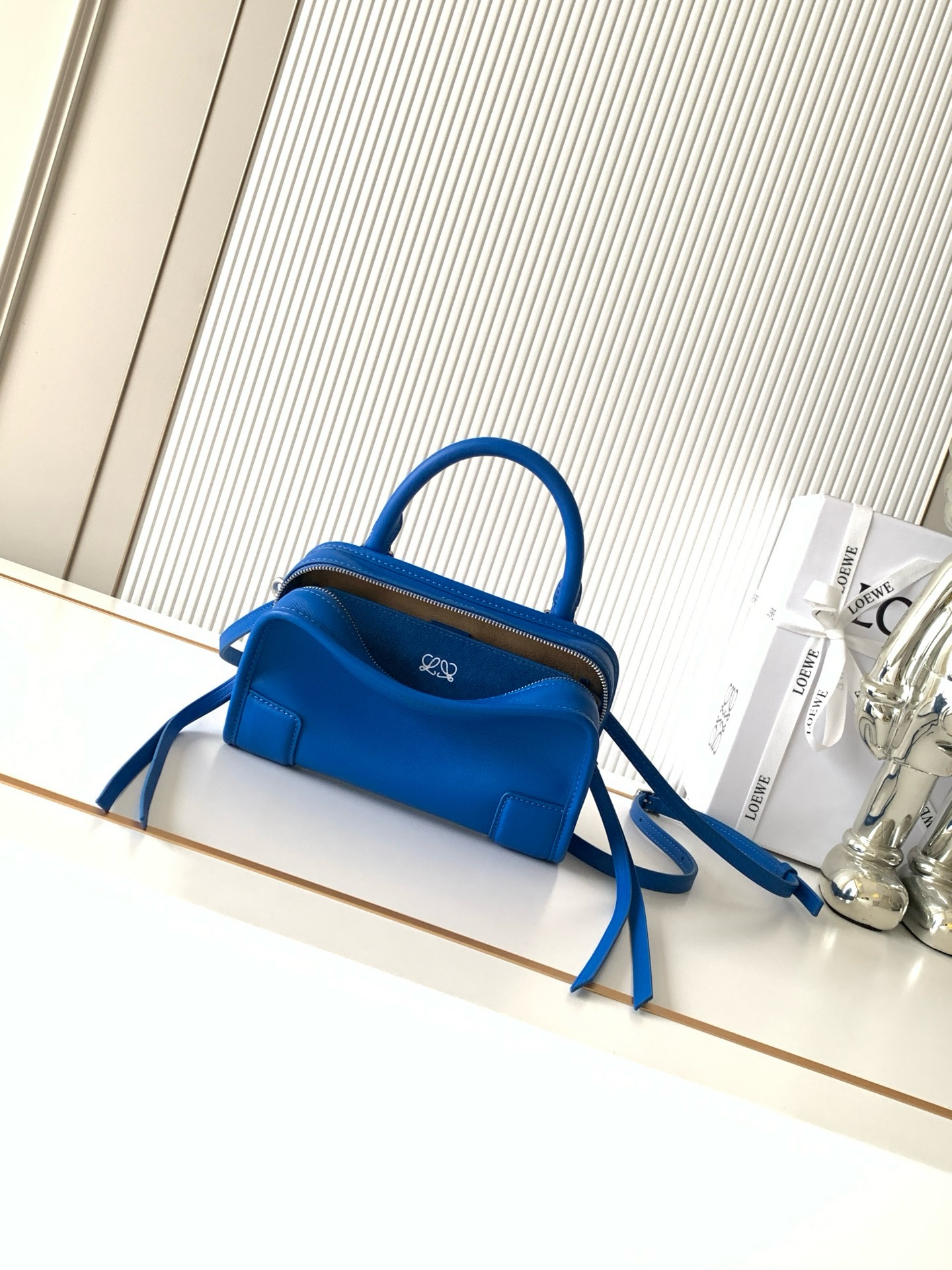 NO:895172,New mini soft calf leather Amazona 180 handbag, same style as Amazona stars  180 reinterprets the legendary bag in a casual silhouette with a single top handle. The bag features an open main compartment with a hidden buckle and a detachable shoulder and cross-body strap for a practical style. This mini version is made from soft calf leather*  Three ways to carry Short handle, detachable shoulder and cross-body strap *Zipper with two leather zipper pulls*Two compartments, main compartment with magnetic closure  L embossed brand logo Size 20CM～11.5CM～7CM Style number 9175 Color royal blue, Loewe, loewe, cowhide19860909新款迷你号柔软牛皮革 Amazona 180 手袋 明星同款Amazona 180重新诠释传奇手袋呈现休闲廓形,搭配单一顶部提手手袋采用开放式设计主隔层以隐藏扣固定搭配可拆卸肩背和斜挎背带打造实用风格.此迷你号版本采用柔软牛皮革制成*三种携带方式短提手、可拆卸肩背和斜挎背带*拉链配有两个皮革拉链头*两个隔层,主隔层以磁扣开合*内部扁平口袋*左侧D形环可定制*织物衬里*烫金或烫银,Double L 压纹品牌标志 尺寸20CM～11.5CM～7CM 款号9175 颜色皇室蓝,罗意威,loewe,cowhide,Bag