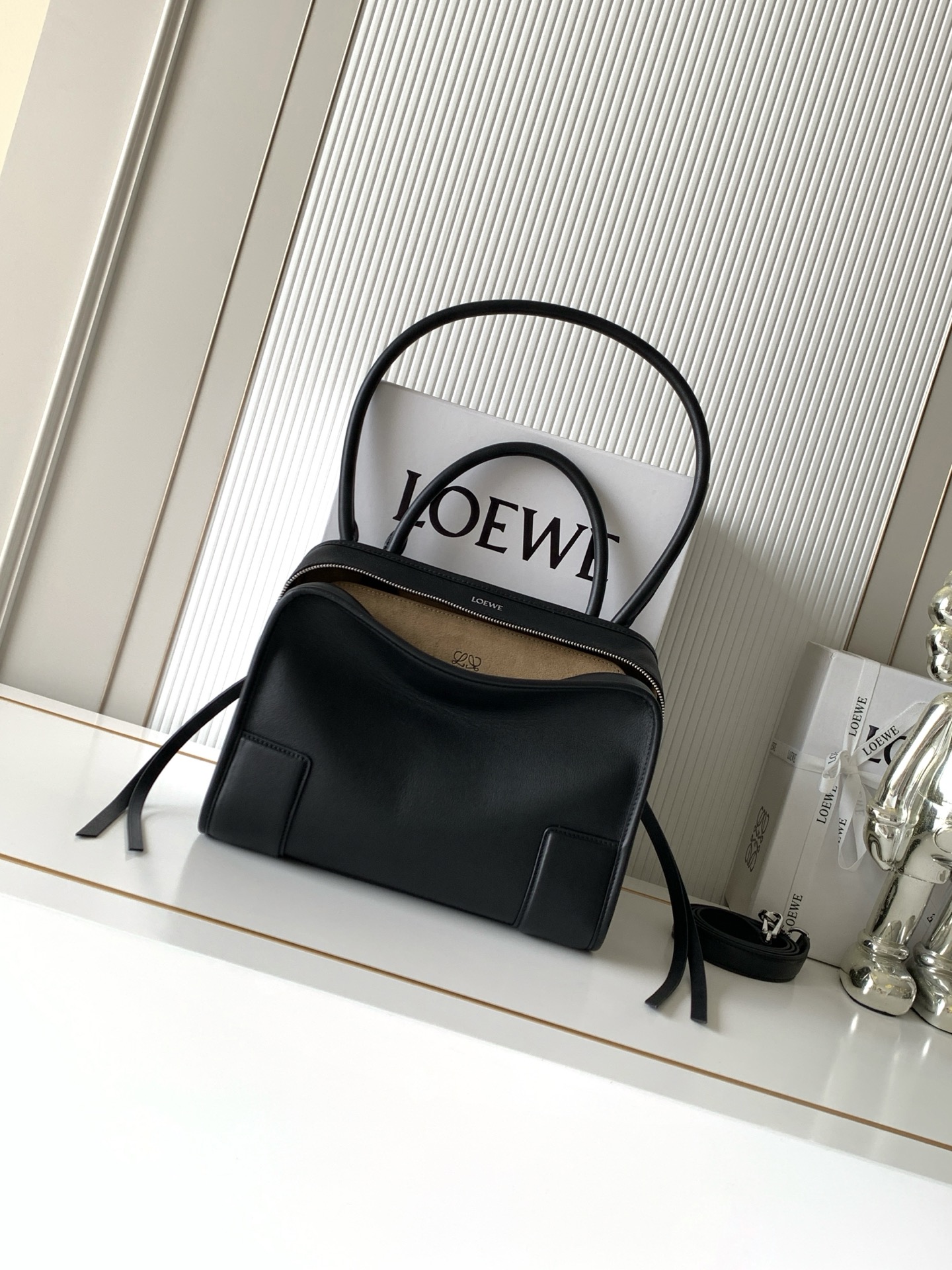 NO:895311,New medium-sized soft cow leather Amazona 180 handbag, the same style as Amazona stars  180 reinterprets the legendary handbag in a casual silhouette with a single top handle. The bag features an open design. The main compartment is secured with a hidden buckle and features a detachable shoulder and cross-body strap for a practical style. This medium version is made from soft calfskin leather*3  Two ways to carry: Short handle, detachable shoulder and cross-body straps *Zipper with two leather zipper pulls*Two compartments, main compartment with magnetic closure  L embossed brand logo Size 28CM～22.5CM～11CM Style number 9182 Color black, Loewe, loewe, cowhide19860909新款中号柔软牛皮革 Amazona 180 手袋 明星同款Amazona 180重新诠释传奇手袋呈现休闲廓形,搭配单一顶部提手手袋采用开放式设计主隔层以隐藏扣固定搭配可拆卸肩背和斜挎背带打造实用风格.此中号版本采用柔软牛皮革制成*三种携带方式短提手、可拆卸肩背和斜挎背带*拉链配有两个皮革拉链头*两个隔层,主隔层以磁扣开合*内部扁平口袋*左侧D形环可定制*织物衬里*烫金或烫银,Double L 压纹品牌标志 尺寸28CM～22.5CM～11CM 款号9182 颜色黑色,罗意威,loewe,cowhide,Bag