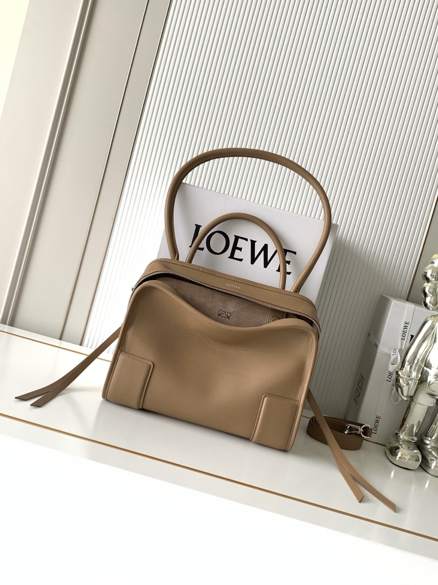 NO:895316,New medium-sized soft cow leather Amazona 180 handbag, the same style as Amazona stars  180 reinterprets the legendary handbag in a casual silhouette with a single top handle. The bag features an open design. The main compartment is secured with a hidden buckle and features a detachable shoulder and cross-body strap for a practical style. This medium version is made from soft calfskin leather*3  Two ways to carry: Short handle, detachable shoulder and cross-body straps *Zipper with two leather zipper pulls*Two compartments, main compartment with magnetic closure  L embossed brand logo Size 28CM～22.5CM～11CM Style number 9182 Color mocha, Loewe, loewe, cowhide19860909新款中号柔软牛皮革 Amazona 180 手袋 明星同款Amazona 180重新诠释传奇手袋呈现休闲廓形,搭配单一顶部提手手袋采用开放式设计主隔层以隐藏扣固定搭配可拆卸肩背和斜挎背带打造实用风格.此中号版本采用柔软牛皮革制成*三种携带方式短提手、可拆卸肩背和斜挎背带*拉链配有两个皮革拉链头*两个隔层,主隔层以磁扣开合*内部扁平口袋*左侧D形环可定制*织物衬里*烫金或烫银,Double L 压纹品牌标志 尺寸28CM～22.5CM～11CM 款号9182 颜色摩卡色,罗意威,loewe,cowhide,Bag
