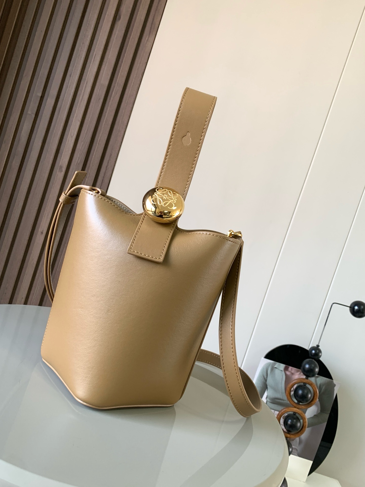 NO:895297,Mini soft grained calfskin Pebble Bucket Pebble cleverly combines pure simple lines with eye-catching design style to create a unique and innovative handbag design. Iconic Anagram  Engraved hardware is both decorative and functional, with an adjustable shoulder strap for multiple carry styles, with a unique twist complemented by subtle details. This mini version is crafted from soft grained calfskin. Can be worn cross-body, over the shoulder or by hand * Adjustable and removable shoulder strap * Magnetic closure * Internal pocket * Synthetic leather lining * Anagram Engraved Pebbles Style No. 9047 Color Oak Brown  Size 20CM～16CM～16CM, Loewe, loewe, cowhide19860909迷你柔软粒面牛皮革 Pebble Bucket 水桶手袋Pebble将纯粹的简约线条与瞩目设计风格巧妙融合造就别具一格的创新的手袋设计.标志性的 Anagram 雕刻五金件兼具装饰和实用功能,可调节肩带长度并适合多种携带方式,独特的扭曲结构与微妙的细节相得益彰.此迷你版本采用柔软粒面牛皮革制成.可斜挎、肩背或手提＊可调节可拆卸肩带＊磁扣开合＊内袋＊合成革衬里* Anagram 雕刻卵石 款号9047 颜色橡木棕 尺寸20CM～16CM～16CM,罗意威,loewe,cowhide,Bag