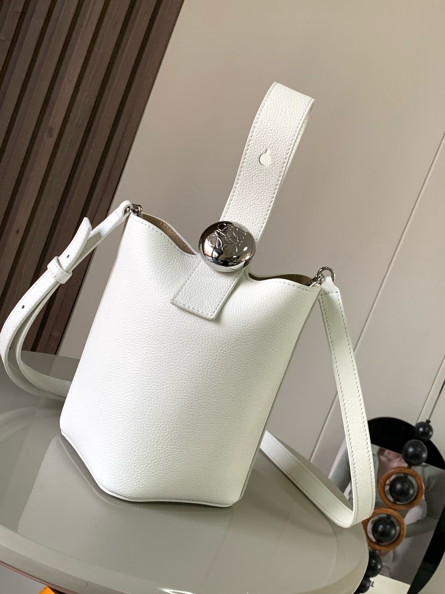 NO:895302,Mini soft grained calfskin Pebble Bucket Pebble cleverly combines pure simple lines with eye-catching design style to create a unique and innovative handbag design. Iconic Anagram  Engraved hardware is both decorative and practical, with an adjustable shoulder strap for multiple carry styles, with a unique twist complemented by subtle details. This mini version is crafted from soft grained calfskin. Can be worn cross-body, over the shoulder or by hand * Adjustable and removable shoulder strap * Magnetic closure * Internal pocket * Synthetic leather lining * Anagram Engraved Pebbles Style No. 9047 Color Off-White  Size 20CM～16CM～16CM, Loewe, loewe, cowhide19860909迷你柔软粒面牛皮革 Pebble Bucket 水桶手袋Pebble将纯粹的简约线条与瞩目设计风格巧妙融合造就别具一格的创新的手袋设计.标志性的 Anagram 雕刻五金件兼具装饰和实用功能,可调节肩带长度并适合多种携带方式,独特的扭曲结构与微妙的细节相得益彰.此迷你版本采用柔软粒面牛皮革制成.可斜挎、肩背或手提＊可调节可拆卸肩带＊磁扣开合＊内袋＊合成革衬里* Anagram 雕刻卵石 款号9047 颜色米白荔 尺寸20CM～16CM～16CM,罗意威,loewe,cowhide,Bag