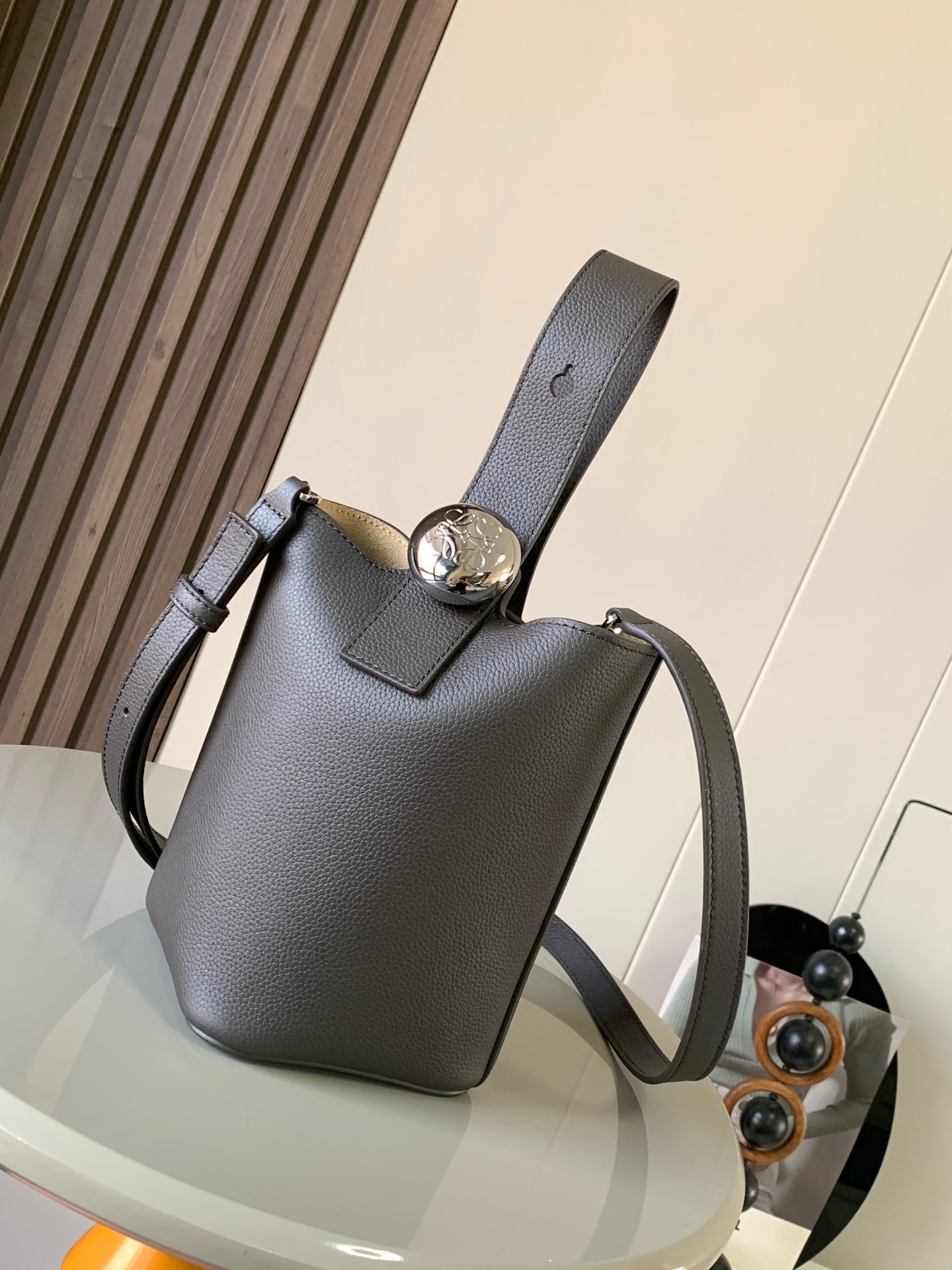 NO:895307,Mini soft grained calfskin Pebble Bucket Pebble cleverly combines pure simple lines with eye-catching design style to create a unique and innovative handbag design. Iconic Anagram  Engraved hardware is both decorative and practical, with an adjustable shoulder strap for multiple carry styles. The unique twist structure complements subtle details. This mini version is crafted from soft grained calf leather. Can be worn cross-body, over the shoulder or by hand * Adjustable and removable shoulder strap * Magnetic closure * Internal pocket * Synthetic leather lining * Anagram Engraved Pebbles Style No. 9047 Color Gray Curry  Size 20CM～16CM～16CM, Loewe, loewe, cowhide19860909迷你柔软粒面牛皮革 Pebble Bucket 水桶手袋Pebble将纯粹的简约线条与瞩目设计风格巧妙融合造就别具一格的创新的手袋设计.标志性的 Anagram 雕刻五金件兼具装饰和实用功能,可调节肩带长度并适合多种携带方式,独特的扭曲结构与微妙的细节相得益彰.此迷你版本采用柔软粒面牛皮革制成.可斜挎、肩背或手提＊可调节可拆卸肩带＊磁扣开合＊内袋＊合成革衬里* Anagram 雕刻卵石 款号9047 颜色灰咖荔 尺寸20CM～16CM～16CM,罗意威,loewe,cowhide,Bag
