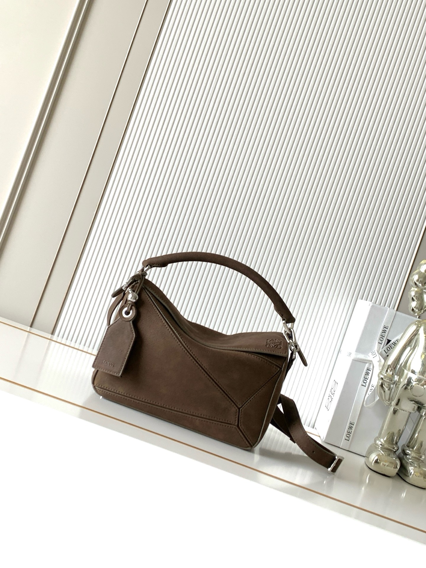 NO:895359,New Geometric Bag Featherlight Puzzle Small Grained Nubuck Featherlight Puzzle Handbag Featherlight Puzzle outlines a rectangular shape with unique geometric lines. This version is made of grained nubuck * Can be worn on the shoulder, cross-body or handheld * Detachable and adjustable shoulder strap with swivel buckle * Zipper closure with hinged zipper pull * One external zippered back pocket and one internal slip pocket * Detachable L0EWE  Hot stamping or hot silver label decorated with secret pockets and balloon dice *Rectangular metal feet *Nappa sheep leather lining *Anagram embossed, L0EWE wording engraved inside the plaque Size 24CM～16.5CM～10.5CM Style No. 9161 Color Nubuck, Loewe, loewe, sheepskin19860909新款几何包 小号粒面牛巴革 Featherlight Puzzle 手袋Featherlight Puzzle 以别具一格的几何线条勾勒长方体造型此版本采用粒面牛巴革制成*可肩背、斜挎或手提*可拆卸可调节肩带饰有旋转卡扣*拉链开合铰接式拉链头*一个外部拉链后袋一个内部插袋*可拆卸L0EWE 烫金或烫银标签饰有隐秘口袋和气球骰子*长方形金属脚钉*纳帕羊皮革衬里*Anagram 压纹、饰牌内部镌刻 L0EWE字样 尺寸24CM～16.5CM～10.5CM 款号9161 颜色牛巴革,罗意威,loewe,sheepskin,Bag