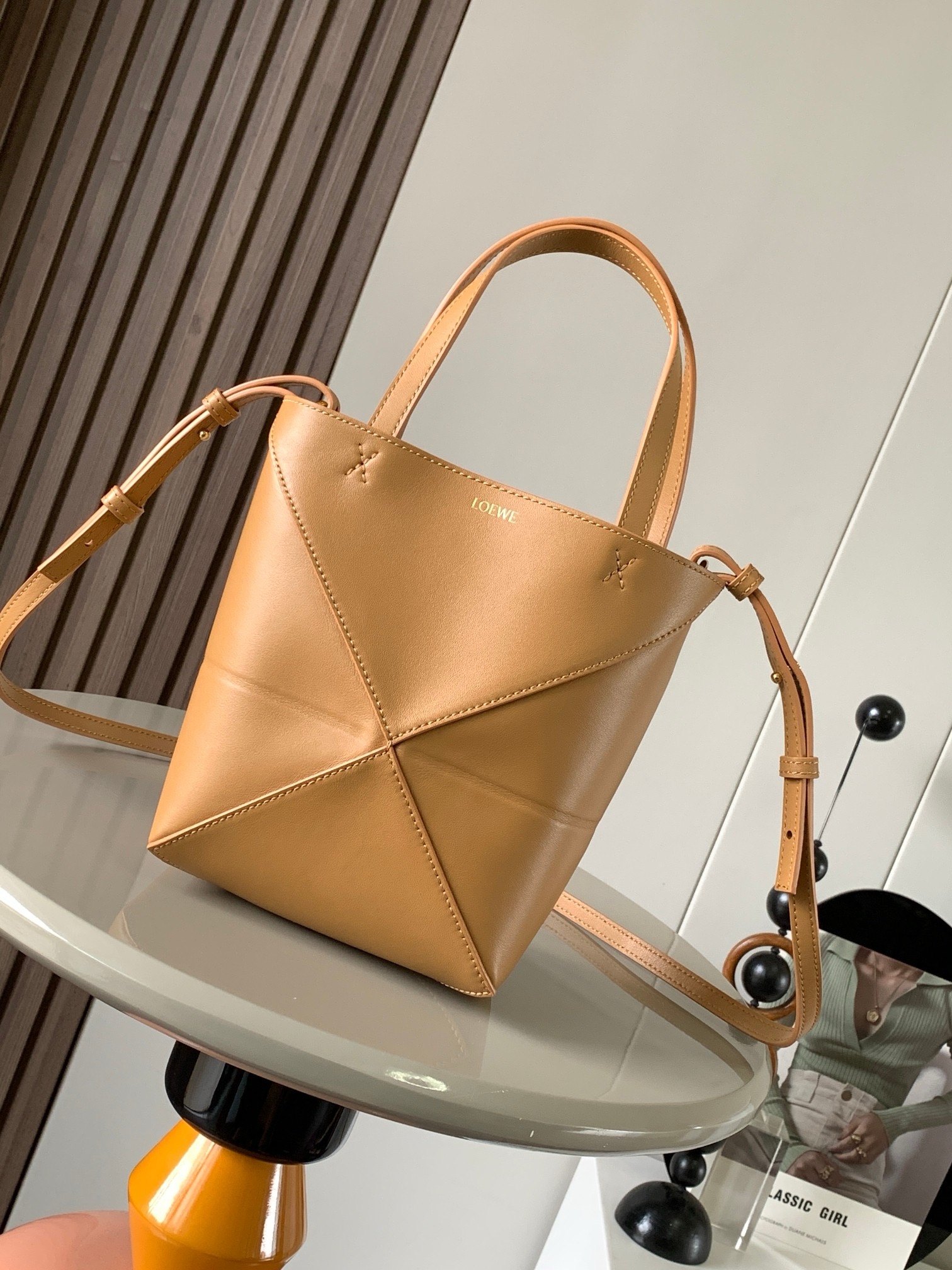 NO:919941,The new glossy cow leather mini puzzle Fold handbag plays with geometric patterns again. It has been a long time since I have seen such a practical and design tote bag. This one continues the geometric aesthetics of the Puzzle series. Inspired by the origami bag, this Puzzle Fold tote can switch between three-dimensional and flat surfaces at will. The leather is very delicate and shiny. It is ultra-light in weight, and the Puzzle can be folded.  The Fold handbag draws inspiration from the geometric lines of the brand's classic handbag series and uses creative ingenuity to reinterpret it into a fashionable tote bag that can be completely folded and is a good travel companion. This mini version is made of soft glossy cowhide. Size 20CM ~ 16.5CM ~ 9CM. Style number 9030. Color: warm sand yellow, Loewe, totes, cowhide19860909新款亮面牛皮革迷你号puzzle Fold手袋又把几何图形玩出花了很久没见过这么实用又设计感满满的托特包了这款延续了Puzzle系列的几何美学以折纸包为灵感,让这只 Puzzle Fold tote 在立体和平面随意切换皮质都很细腻光泽本身自重超轻,外加可以折叠Puzzle Fold手袋从品牌经典手袋系列的几何线条汲取灵感运用创意巧思将其重新诠释为一款时尚的托特袋,能完全折叠是旅行良伴.这个迷你号版本采用柔软的亮面牛皮革打造 尺寸20CM～16.5CM～9CM 款号9030 颜色暖沙黄,罗意威,loewe,totes,cowhide,Bag