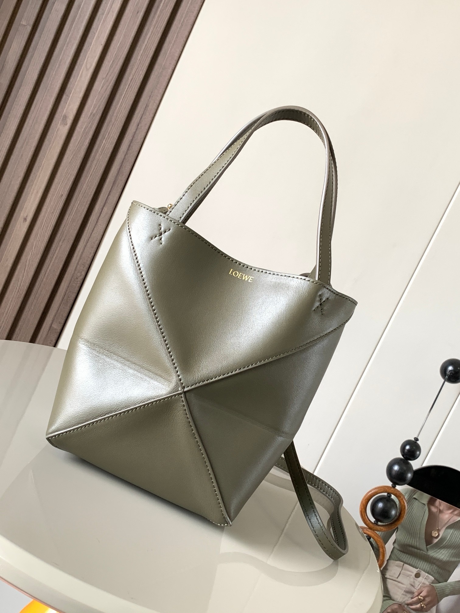 NO:919943,The new glossy cow leather mini puzzle Fold handbag plays with geometric patterns again. It has been a long time since I have seen such a practical and design tote bag. This one continues the geometric aesthetics of the Puzzle series. Inspired by the origami bag, this Puzzle Fold tote can switch between three-dimensional and flat surfaces at will. The leather is very delicate and shiny. It is ultra-light in weight, and the Puzzle can be folded.  The Fold handbag draws inspiration from the geometric lines of the brand's classic handbag series and uses creative ingenuity to reinterpret it into a fashionable tote bag that can be fully folded and is a good travel companion. This mini version is made of soft glossy cowhide. Size 20CM～16.5CM～9CM. Style No. 9030. Color: khaki green, Loewe, loewe, totes, cowhide19860909新款亮面牛皮革迷你号puzzle Fold手袋又把几何图形玩出花了很久没见过这么实用又设计感满满的托特包了这款延续了Puzzle系列的几何美学以折纸包为灵感,让这只 Puzzle Fold tote 在立体和平面随意切换皮质都很细腻光泽本身自重超轻,外加可以折叠Puzzle Fold手袋从品牌经典手袋系列的几何线条汲取灵感运用创意巧思将其重新诠释为一款时尚的托特袋,能完全折叠是旅行良伴.这个迷你号版本采用柔软的亮面牛皮革打造 尺寸20CM～16.5CM～9CM 款号9030 颜色卡其绿,罗意威,loewe,totes,cowhide,Bag
