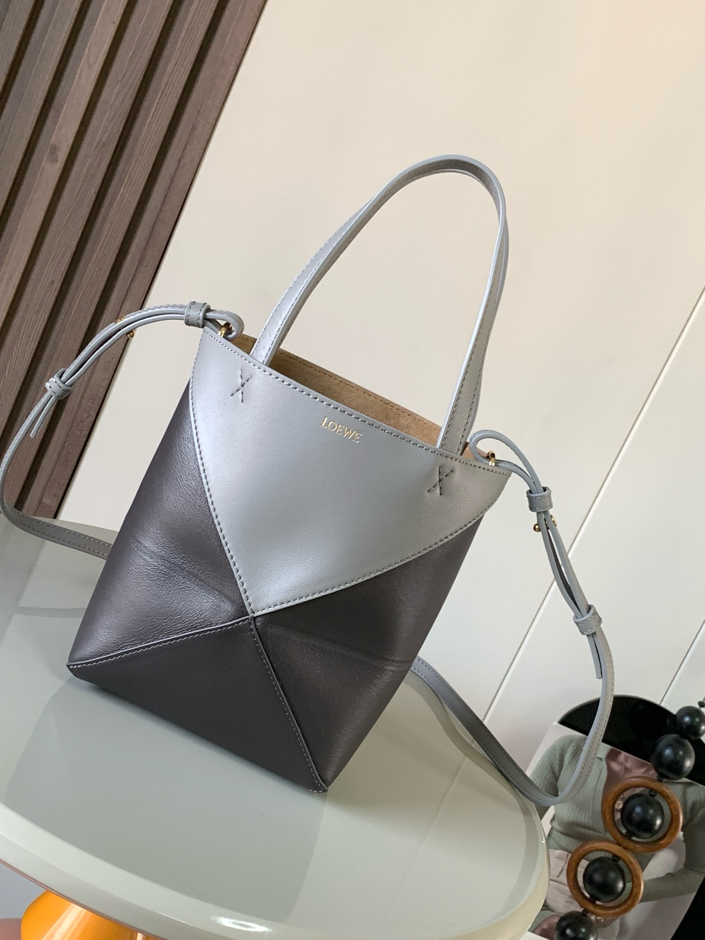 NO:919958,The new glossy cow leather mini puzzle Fold handbag plays with geometric patterns again. It has been a long time since I have seen such a practical and design tote bag. This one continues the geometric aesthetics of the Puzzle series. Inspired by the origami bag, this Puzzle Fold tote can switch between three-dimensional and flat surfaces at will. The leather is very delicate and shiny. It is ultra-light in weight, and the Puzzle can be folded.  The Fold handbag draws inspiration from the geometric lines of the brand's classic handbag series and uses creative ingenuity to reinterpret it into a fashionable tote bag that can be completely folded and is a good travel companion. This mini version is made of soft glossy cow leather. Size 20CM～16.5CM～9CM. Style No. 9030. Color: Asphalt Gray, Loewe, Totes, Cowhide19860909新款亮面牛皮革迷你号puzzle Fold手袋又把几何图形玩出花了很久没见过这么实用又设计感满满的托特包了这款延续了Puzzle系列的几何美学以折纸包为灵感,让这只 Puzzle Fold tote 在立体和平面随意切换皮质都很细腻光泽本身自重超轻,外加可以折叠Puzzle Fold手袋从品牌经典手袋系列的几何线条汲取灵感运用创意巧思将其重新诠释为一款时尚的托特袋,能完全折叠是旅行良伴.这个迷你号版本采用柔软的亮面牛皮革打造 尺寸20CM～16.5CM～9CM 款号9030 颜色沥青灰咖灰,罗意威,loewe,totes,cowhide,Bag