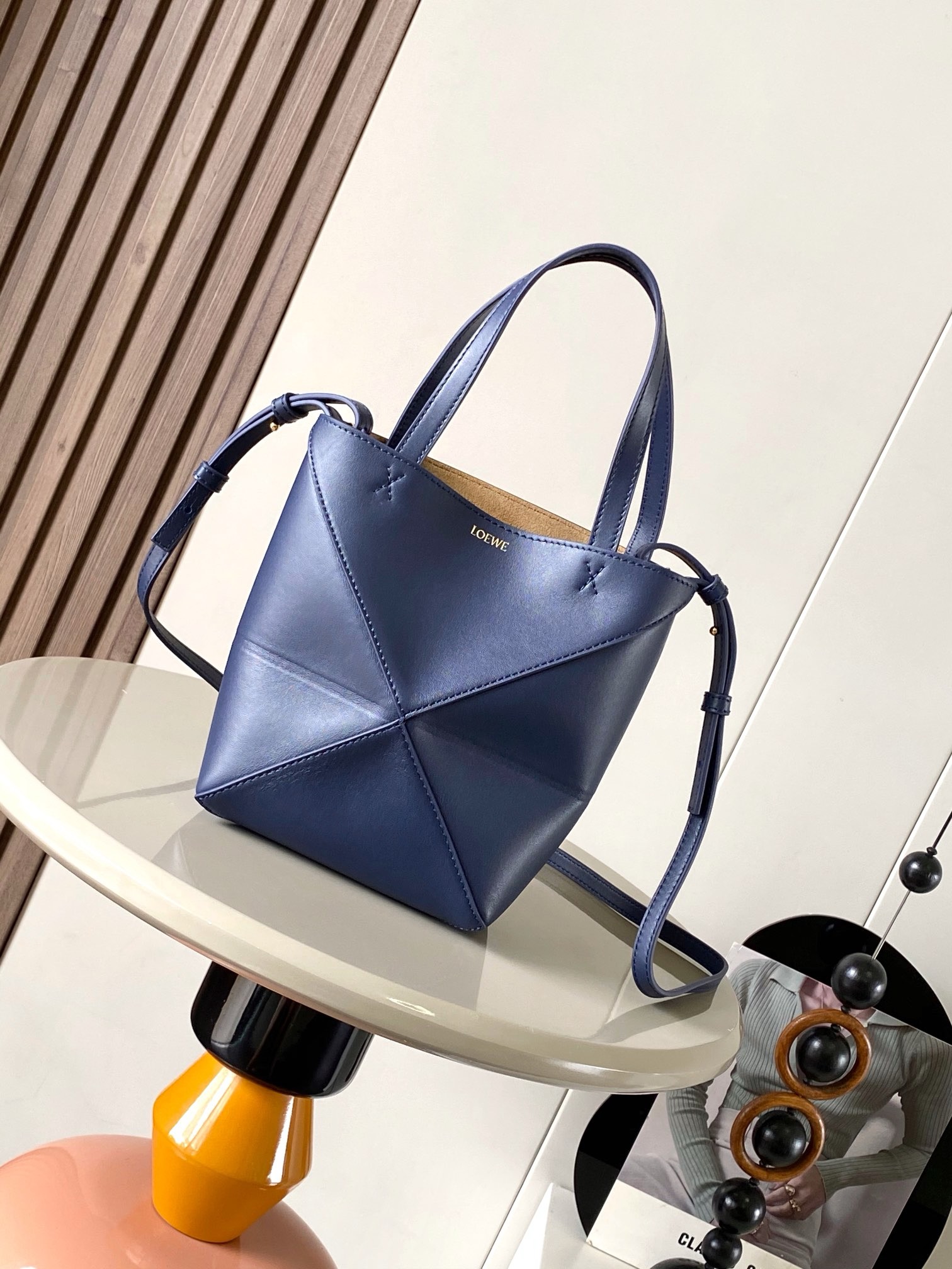 NO:919933,The new glossy cow leather mini puzzle Fold handbag plays with geometric patterns again. It has been a long time since I have seen such a practical and design tote bag. This one continues the geometric aesthetics of the Puzzle series. Inspired by the origami bag, this Puzzle Fold tote can switch between three-dimensional and flat surfaces at will. The leather is very delicate and shiny. It is ultra-light in weight, and the Puzzle can be folded.  The Fold handbag draws inspiration from the geometric lines of the brand's classic handbag series and uses creative ingenuity to reinterpret it into a fashionable tote bag that can be fully folded and is a good travel companion. This mini version is made of soft glossy cowhide. Size 20CM～16.5CM～9CM. Style No. 9030. Color: navy blue, Loewe, loewe, totes, cowhide19860909新款亮面牛皮革迷你号puzzle Fold手袋又把几何图形玩出花了很久没见过这么实用又设计感满满的托特包了这款延续了Puzzle系列的几何美学以折纸包为灵感,让这只 Puzzle Fold tote 在立体和平面随意切换皮质都很细腻光泽本身自重超轻,外加可以折叠Puzzle Fold手袋从品牌经典手袋系列的几何线条汲取灵感运用创意巧思将其重新诠释为一款时尚的托特袋,能完全折叠是旅行良伴.这个迷你号版本采用柔软的亮面牛皮革打造 尺寸20CM～16.5CM～9CM 款号9030 颜色海军蓝,罗意威,loewe,totes,cowhide,Bag