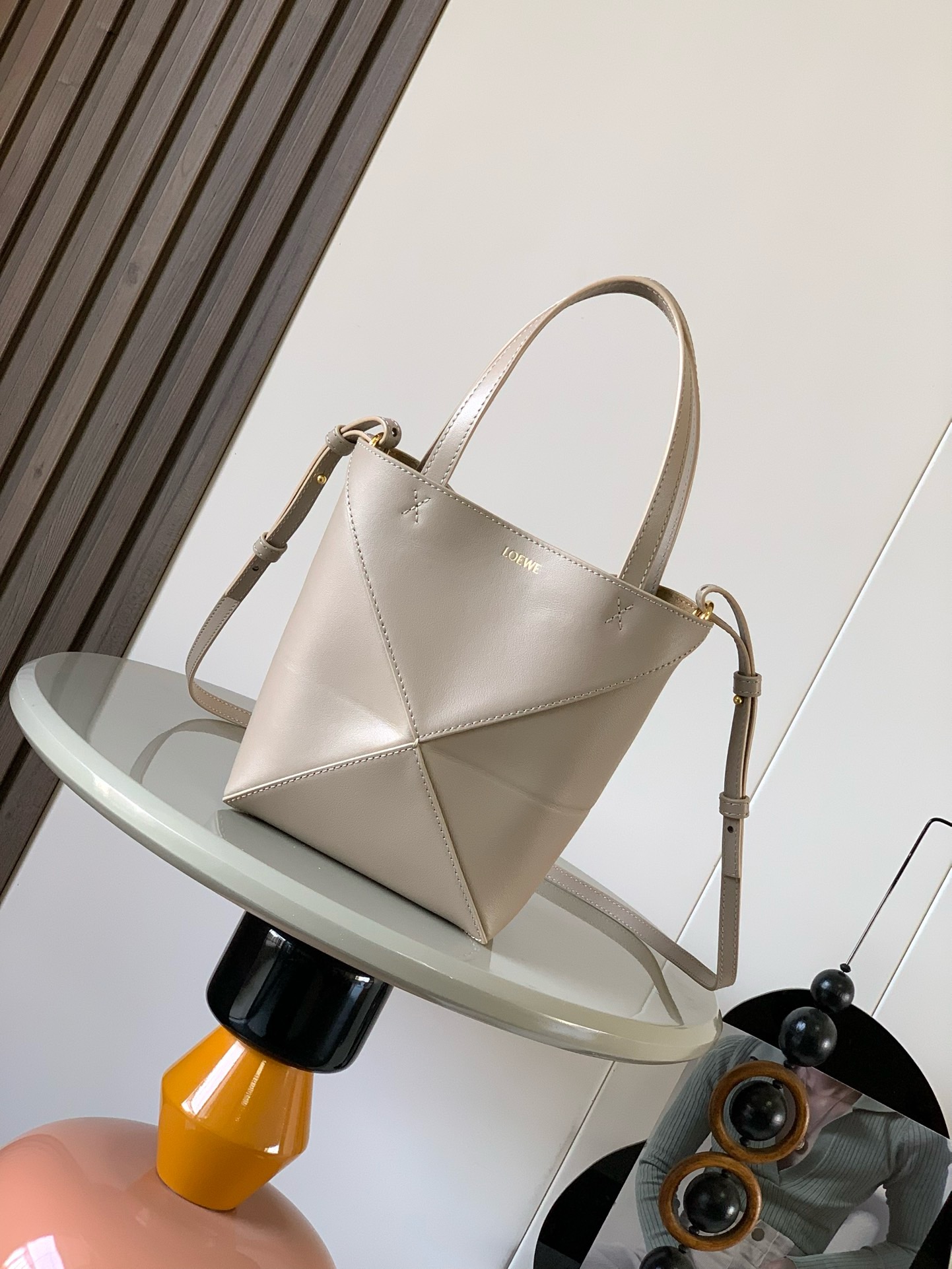 NO:919937,The new glossy cow leather mini puzzle Fold handbag plays with geometric patterns again. It has been a long time since I have seen such a practical and design tote bag. This one continues the geometric aesthetics of the Puzzle series. Inspired by the origami bag, this Puzzle Fold tote can switch between three-dimensional and flat surfaces at will. The leather is very delicate and shiny. It is ultra-light in weight, and the Puzzle can be folded.  The Fold handbag draws inspiration from the geometric lines of the brand's classic handbag series and uses creative ingenuity to reinterpret it into a fashionable tote bag that can be completely folded and is a good travel companion. This mini version is made of soft glossy cowhide. Size 20CM～16.5CM～9CM. Style No. 9030. Color: gravel, Loewe, totes, cowhide.19860909新款亮面牛皮革迷你号puzzle Fold手袋又把几何图形玩出花了很久没见过这么实用又设计感满满的托特包了这款延续了Puzzle系列的几何美学以折纸包为灵感,让这只 Puzzle Fold tote 在立体和平面随意切换皮质都很细腻光泽本身自重超轻,外加可以折叠Puzzle Fold手袋从品牌经典手袋系列的几何线条汲取灵感运用创意巧思将其重新诠释为一款时尚的托特袋,能完全折叠是旅行良伴.这个迷你号版本采用柔软的亮面牛皮革打造 尺寸20CM～16.5CM～9CM 款号9030 颜色砂砾色,罗意威,loewe,totes,cowhide,Bag