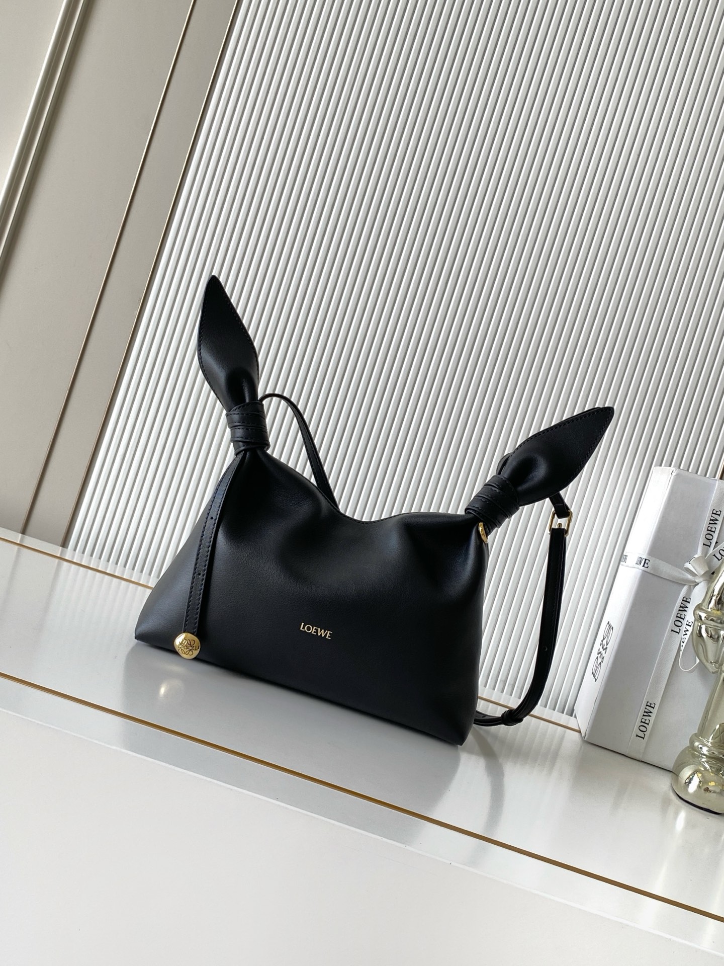 NO:941915,Mini Scarf bag in smooth calfskin The Scarf bag is made from two pieces of fabric, elegantly tied with leather knots and decorated with a new twist. The Pebble signature silhouette is clean, chic and feminine, reminiscent of a knotted scarf. This mini version is made of smooth calfskin *Adjustable leather strap*Can be worn by hand, shoulder or crossbody*Magnetic closure*Suede lining' Engraved Anagram Pebble *L0EWE Hot stamped or silvered  Size 24.5CM～14.5CM～6CM Style number 9187 Color black, Loewe, loewe, cowhide19860909迷你号光滑牛皮革 Scarf 手袋Scarf手袋由两片布料构成透过皮革绳结优雅系合并饰有全新扭曲效果 Pebble 标志廓形简洁别致且充满柔美魅力让人不禁联想到系结围巾. 此迷你号版本采用光滑牛皮革制成*可调节皮革肩带*可手提、肩背或斜挎*磁扣开合*绒面革衬里“镌刻Anagram Pebble *L0EWE 烫金或烫银 尺寸24.5CM～14.5CM～6CM 款号9187 颜色黑色,罗意威,loewe,cowhide,Bag