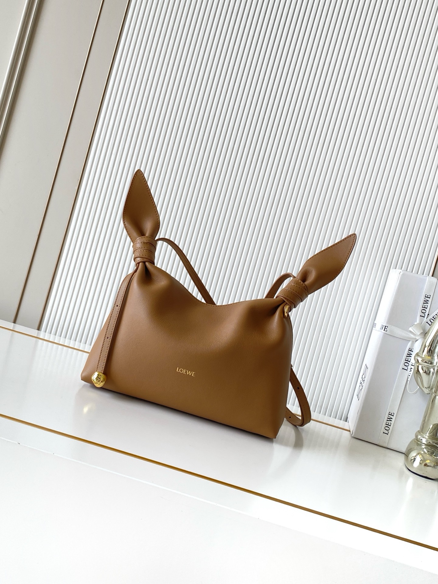 NO:941923,Mini Scarf bag in smooth calfskin The Scarf bag is made from two pieces of fabric, elegantly tied with leather knots and decorated with a new twist. The Pebble signature silhouette is clean, chic and feminine, reminiscent of a knotted scarf. This mini version is made of smooth calfskin *Adjustable leather strap*Can be worn by hand, shoulder or crossbody*Magnetic closure*Suede lining' Engraved Anagram Pebble *L0EWE Hot stamped or silvered  Size 24.5CM～14.5CM～6CM Style No. 9187 Color Mocha, Loewe, loewe, cowhide19860909迷你号光滑牛皮革 Scarf 手袋Scarf手袋由两片布料构成透过皮革绳结优雅系合并饰有全新扭曲效果 Pebble 标志廓形简洁别致且充满柔美魅力让人不禁联想到系结围巾. 此迷你号版本采用光滑牛皮革制成*可调节皮革肩带*可手提、肩背或斜挎*磁扣开合*绒面革衬里“镌刻Anagram Pebble *L0EWE 烫金或烫银 尺寸24.5CM～14.5CM～6CM 款号9187 颜色摩卡色,罗意威,loewe,cowhide,Bag