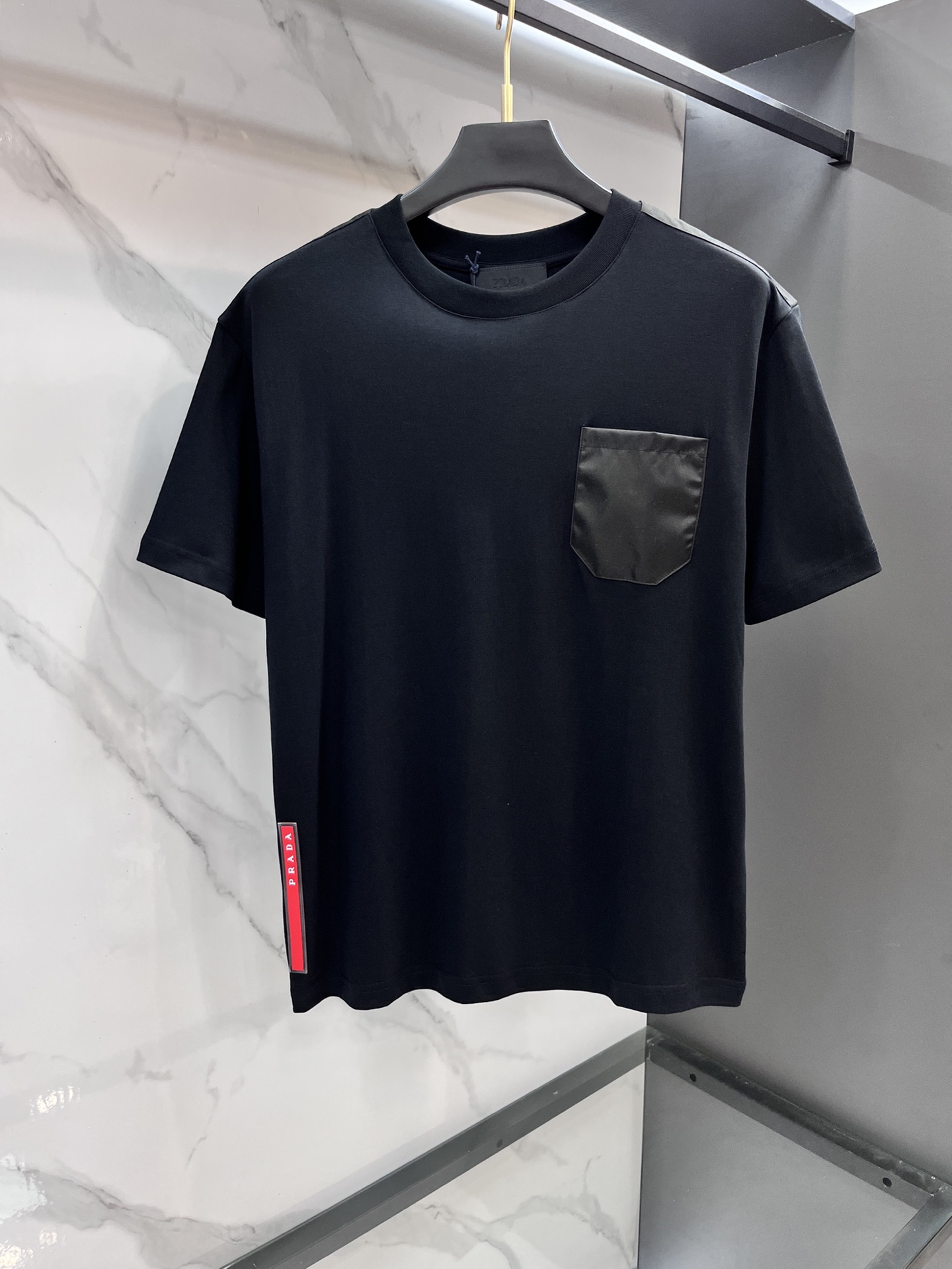 NO:514408,Prada triangular logo inlay pocket short-sleeved T-shirt, custom helium mercerized satin fabric, iconic enameled triangular metal logo decorative sleeves, blended re-nylon nylon fabric embellished square silhouette, cross-field aesthetic grafting, exquisite small pocket design, highlighting quality and style. The infrared positioning of the 'prada triangle mark' is used to use imported special aircraft infrared positioning, more precise and firm. Needle shuttle splicing technology can make full use of the respective advantages of knitted fabric and woven fabric. By choosing the right sewing process and stitching, the splicing parts can be ensured to be firm and beautiful.19860909普拉达 三角标嵌饰口袋短袖T恤,定制氦蚀丝光棱缎面料,标志性涂珐琅三角形金属徽标装饰衣袖,融合re-nylon尼龙织物点缀方正廓形,跨领域美学嫁接,精致的小口袋设计,彰显品质与格调.采用进口专机红外线定位”prada三角标“位置更为精准 牢固结实.针梭拼接技术,能够充分利用针织面料和梭织面料的各自优点,通过选择合适的缝制工艺和线迹,可以确保拼接部位牢固且美观.…………………………………………………… SizeM-XXXL,,prada,prada,T-shirt,tees，t-shirt,alexander wang,Men's clothing