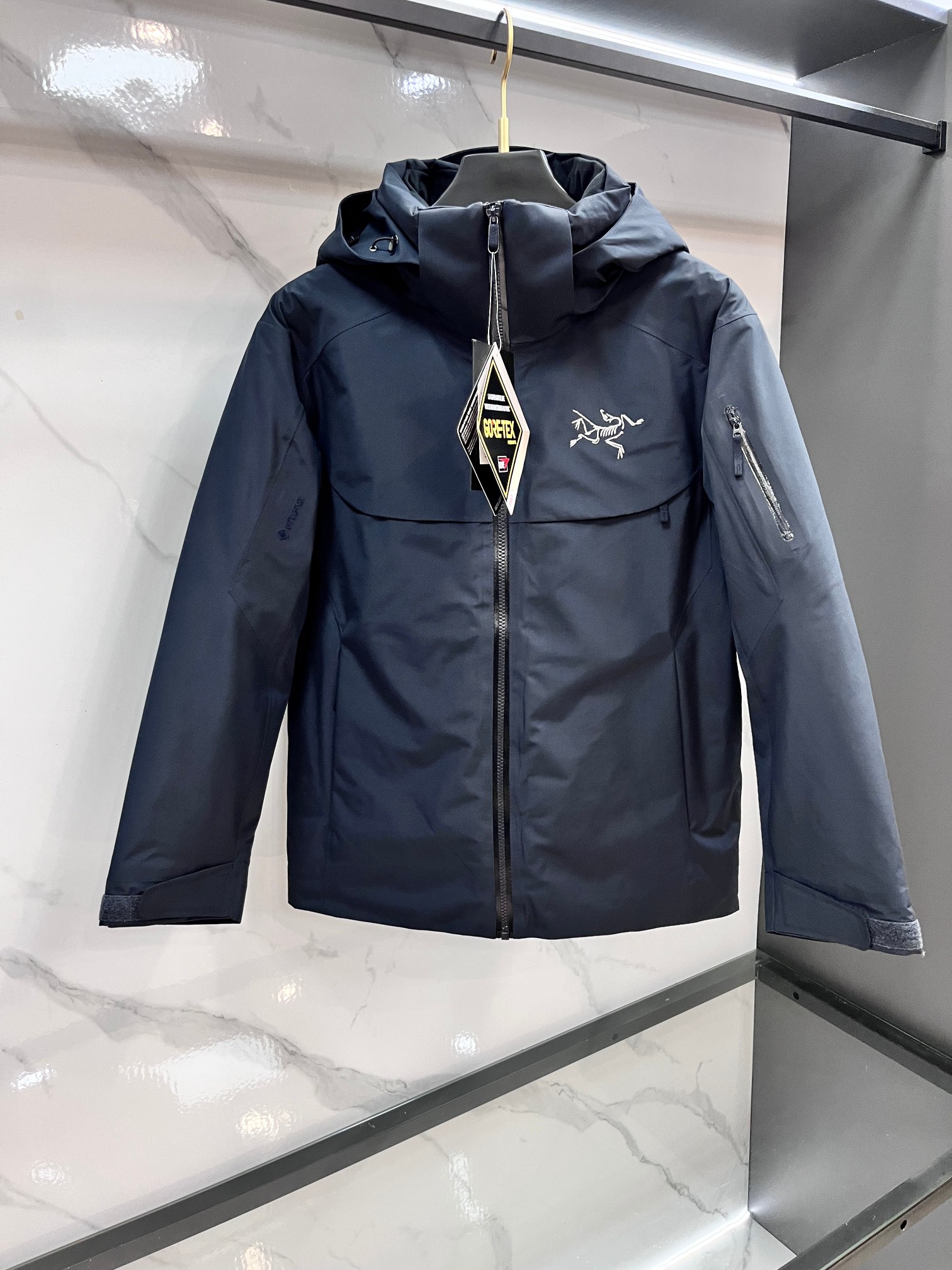 NO:622686,Arc'teryx (top version) 2025 winter new ARCTERYX Arc'teryx Macai Jacket (Damaicai) Professional-grade ski down jacket｜GORE-TEX protection｜750 fleece|China version optimization 2025 winter new Macai Jacket, Arc'teryx's peak ski equipment has been upgraded!  The GORE-TEX embroidery has been moved from the sleeve shoulders to the cuffs, making it more concise and practical; the fabric and filling have been fully upgraded - the outer layer is made of GORE-TEX  3L three-layer structure, with stronger windproof, waterproof and breathable performance; the filling is upgraded to national standard 90 white goose down (750 fill power), which is larger and warmer, bringing the ultimate cold-proof experience. Especially optimized for the body shape of Chinese users, the sleeve length is shortened by 1-2cm, and the bust and hem are reduced by 4cm, saying goodbye to the bloated feeling of traditional ski suits, and the slim tailoring is more neat. Professional ski function design, no fear of extreme environments. Down Composite  Mapping technology accurately lays out thermal insulation materials, distributing Coreloft synthetic fibers in areas prone to moisture such as the hood, hem and armpits, so that it can continue to keep warm in humid environments; 750 cubic inches of European goose down are concentrated in the core torso and sleeves to provide sufficient heat for the body. The DropHood detachable hood is  Compatible with standard single/double board ski helmets, the laminated brim is designed to rotate freely with the head, preventing wind and snow while maintaining a clear field of vision. The detachable wind skirt is equipped with high-density tape to effectively block the intrusion of powder snow; the mesh PowderGuard armpit vents and the mesh WaterTight main zipper provide both wind and snow protection and rapid heat dissipation.  Details highlight professional quality. The whole garment adopts GORE-TEX three-layer structure and fully taped seam technology, which is more weatherproof and permeable. The smooth inner fabric is easy to wear in layers. The three-dimensional plastic tailoring fits the Asian body shape and allows for more freedom of movement. Designs such as rubberized brim, adjustable drawstring, and helmet-compatible hood protect warmth in all directions. Hidden zipper sleeve pockets and multi-pocket layout on the inside are both practical and protective. The detachable wind skirt at the bottom is equipped with elastic bands and snaps to adapt to different pants types.………………………………………………………………  SizeM-XXXL,arc'teryx,skirts,down jacket,hats,alexander wang19860909始祖鸟（顶级版本）2025冬季新款 ARCTERYX始祖鸟Macai Jacket（大买菜） 专业级滑雪羽绒服｜GORE-TEX防护｜750蓬欧绒｜中国版型优化 2025冬季新款大买菜系列Macai Jacket,始祖鸟巅峰滑雪装备再升级！GORE-TEX刺绣从袖肩移至袖口,更显简洁实用；面料与填充全面进阶——外层采用GORE-TEX 3L三层结构,防风防水透气性能更强；填充升级为国标90白鹅绒（750蓬松度）,绒朵更大更保暖,带来极致御寒体验.特别针对中国用户身形优化,袖长缩短1-2cm,胸围与下摆缩减4cm,告别传统滑雪服的臃肿感,修身剪裁更显利落. 专业滑雪功能设计,无惧极端环境.Down Composite Mapping技术精准布局保暖材料,将Coreloft合成纤维分布于帽兜、下摆和腋下等易湿部位,潮湿环境仍能持续保暖；750立方英寸欧洲鹅绒集中于核心躯干及袖部,为身体提供充足热量.DropHood可拆卸风帽兼容标准单/双板滑雪头盔,压胶帽檐设计随头部自由转动,防风雪同时保持视野清晰.可拆卸风裙搭配高密度胶条,有效阻隔粉雪倒灌；网眼PowderGuard腋下通风口与网状WaterTight主拉链,兼顾防风雪与快速散热. 细节彰显专业品质.整衣采用GORE-TEX三层结构与全贴带接缝工艺,防风雨渗透性更强,光滑内面面料方便分层穿搭；立体整形剪裁贴合亚洲人身形,活动更自如.压胶帽沿、可调抽绳、头盔兼容风帽等设计,全方位守护温暖.隐藏式拉链袖袋、内侧多口袋布局,兼顾实用与防护.底部可拆卸风裙配橡筋和按扣,适配不同裤型.…………………………………………………… SizeM-XXXL,arc'teryx,skirts,down jacket,hats,alexander wang,Men's clothing