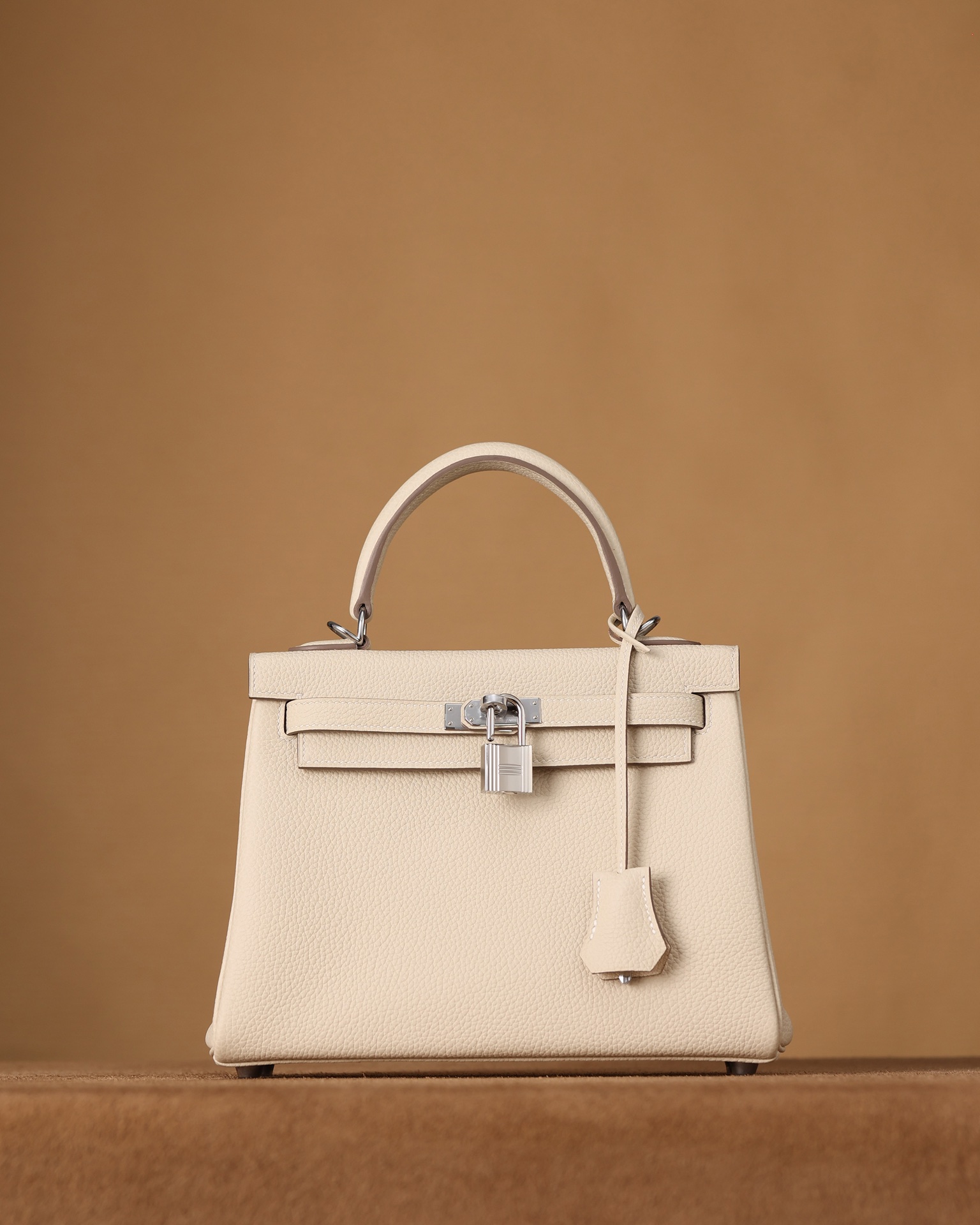 Channel goods, 95% authentic, with actual photos. H-Kelly 25cm in milk tea white with platinum hardware in togo leather. Exclusive channel goods, sourced from the exclusive H website channel (one of a kind). Imported togo leather, made from top layer calfskin (please specify grain pattern when ordering). Lightweight, durable, comfortable to touch, with a glossy finish. Original design, with authentic packaging. Size: 25cm X 17cm X 7cm. Channel goods: 9965088750 (handmade), 9955088650 (pure handmade), 9917588225 (semi-handmade), 998588125 (motorcycle). image 1