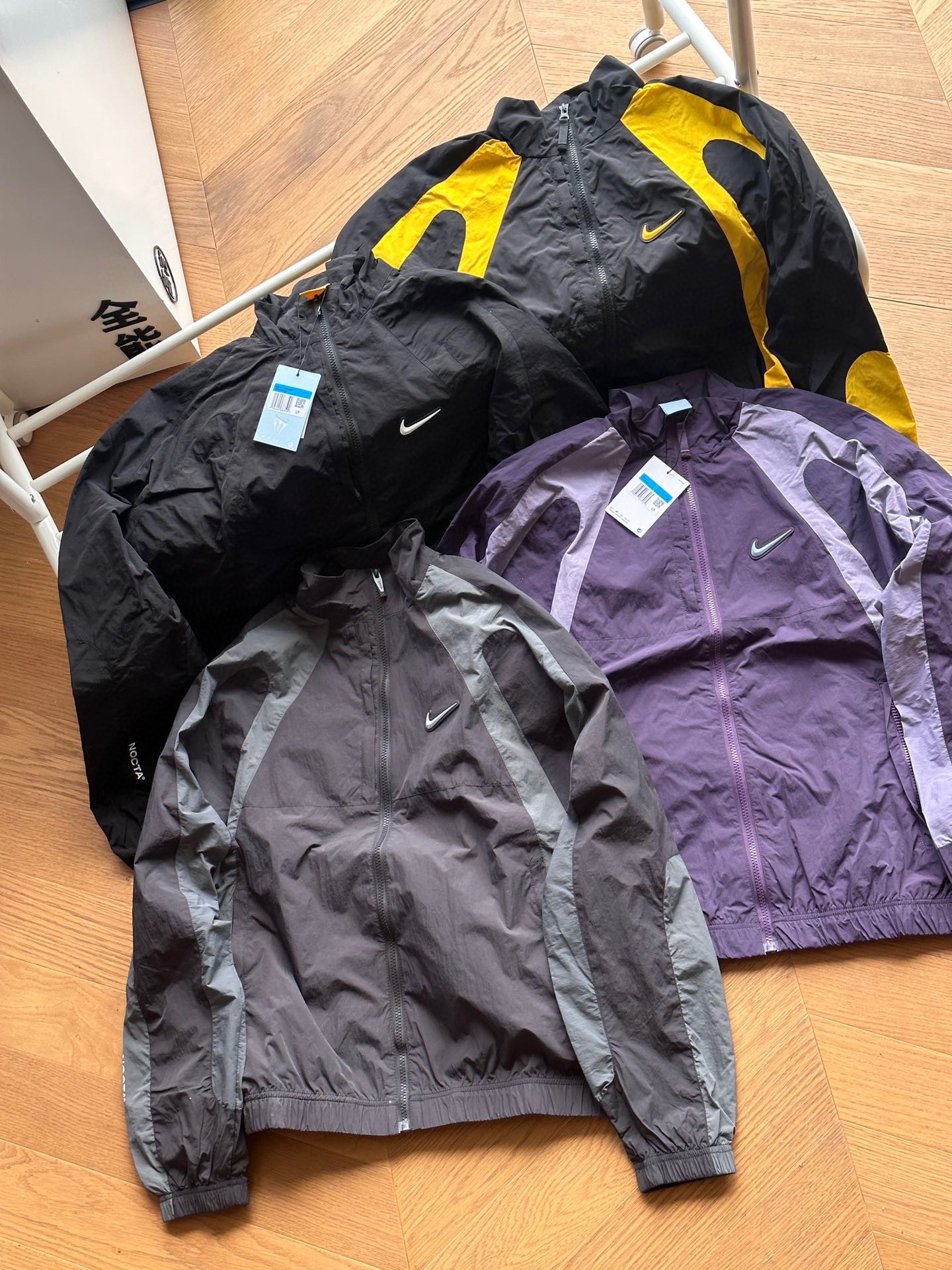 【四色高版本】供外套💰180 裤子💰180 可单发🇷🇺Nike X Drake 联名款 NOCTA系列撞色轻薄款立领夹克外套裤子套装🇷🇺男女同款 
 
灰色 黑色白标 紫色 黑色黄标 
S~XL

🌘面料采用梭织原版定制，功能性防水面料，3D剪裁拼色设计，logo印花全部采用原版印花，胸口硅胶钩子。

🌘全套原版三标辅料齐全

尺码表：
175 120穿s合适
外套：
S：胸围110衣长68肩宽52
M：胸围114衣长70 肩宽53.5
L：胸围118 衣长72肩宽55
XL：胸围122衣长74肩宽56.5

裤子：
S   裤长93     腰围75   臀围 104 
M  裤长94.5  腰围79   臀围 108
L   裤长96     腰围83   臀围 112
XL  裤长97.5  腰围87   臀围 116