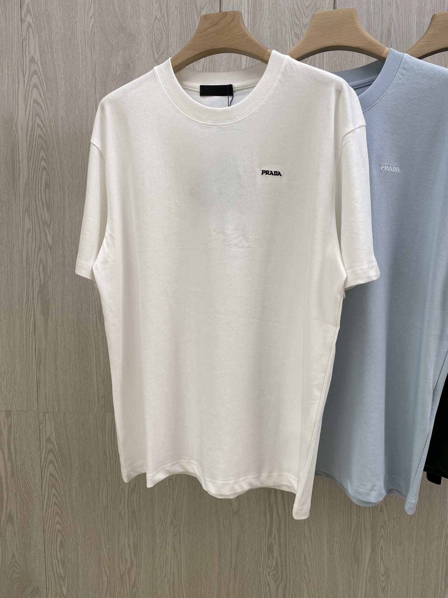 NO:449699,.PD Summer New Favorite~ Small letter embroidery four-color pure cotton short-sleeved T-shirt Small embroidery, big identity - Pra**'s low-key announcement!  The exquisite small letter embroidery on the chest is the 'identity seal' engraved in the genes by Pra**. There is no exaggerated pattern and does not rely on large-scale printing to attract attention. Just a small piece, people who understand it will naturally understand. It is made of pure cotton, breathable and not sweaty, and can keep it refreshing even if you wear it at 38 degrees in summer; it is first-class in moisture absorption, and you can wipe it off easily when you exercise and sweat, and it will dry one step faster than others. The fabric has a slightly old feeling, which is softer and more delicious as it goes on. The same style as men and women, black green white light blue, XS-L size!  1-3CM error in flat measurement XS code: shoulder width 50 bust 106 clothes length 69 sleeves 22 S code: shoulder width 51 bust 110 clothes length 71 sleeves 22.5 M code: shoulder width 52 bust 114 clothes length 73 sleeves 23 L code: shoulder width 53 bust 118 clothes length 75 sleeves 23.5 Girls choose XS code; boys choose XS code below 135 catties; 135-150 catties choose S code; 150-165 catties choose M code; 165-185 catties choose L code.,,prada,T-shirt,tees,t-shirt,alexander wang19860909.PD夏日新宠~小字母刺绣四色款纯棉短袖T恤 小刺绣,大身份——Pra**的低调宣告！胸前精致的小字母刺绣,是 Pra**刻在基因里的 “身份印章” .没有浮夸图案,不靠大面积印花博眼球,就这么小小一枚,懂的人自然懂. 纯棉材质,透气不闷汗,夏天38度穿也能保持清爽；吸湿性一流,运动出汗随手一擦,干得比别人快一步 .面料自带微微做旧感,越穿越软、越穿越有味道的一件 T 恤. 男女同款,黑色 绿色 白色 浅蓝色,XS-L码！ 平铺测量1-3CM误差 XS码:肩宽50胸围106衣长69袖子22 S码:肩宽51胸围110衣长71袖子22.5 M码:肩宽52胸围114衣长73袖子23 L码:肩宽53胸围118衣长75袖子23.5 女生选择XS码； 男生 135斤以下选择XS码；135-150斤选择S码； 150-165斤选择M码；165-185斤选择L码.,,prada,T-shirt,tees，t-shirt,alexander wang,Men's clothing