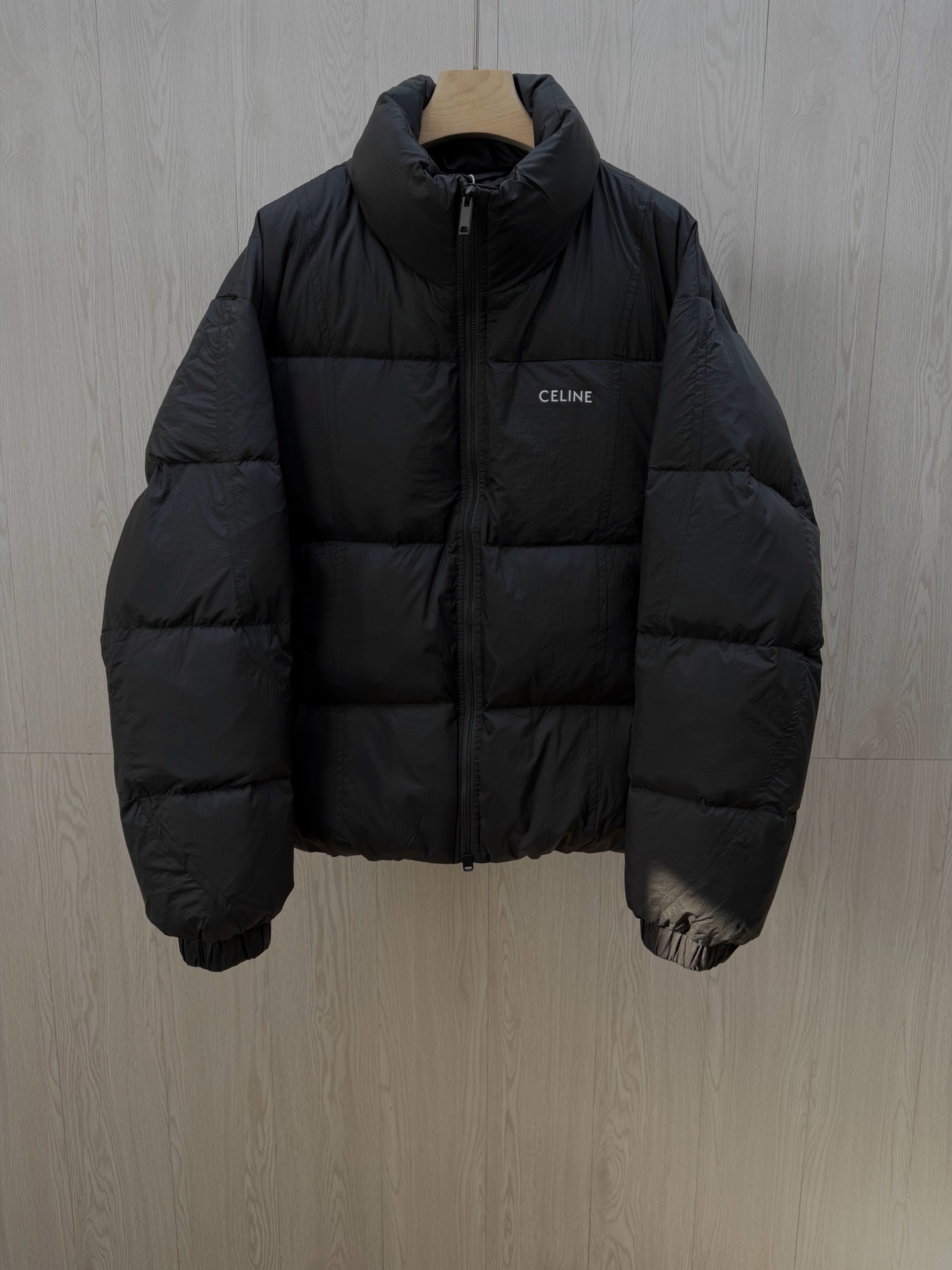 NO:712144,CEL** Frosted Black High-Filled Down Jacket This frosted black down jacket combines French minimalist aesthetics with high-end thermal performance, becoming a luxurious addition to your autumn and winter wardrobe.  The body is made of nylon matte fabric. The matte black tone has a low-key luxury atmosphere. The fabric is wind-resistant, wear-resistant and light and drapey. It has no stiffness like ordinary down fabrics when touched, showing the brand's exquisite texture. The interior is filled with 90 white duck down and is designed with a high filling capacity, which has excellent bulk and warmth. The three-dimensional plaid quilting process firmly locks the down to avoid running down and clumping, and can maintain comfort and warmth even in low temperature environments.  The classic stand-up collar silhouette is optimized for loose tailoring, and the minimalist white CELI** letter logo print on the chest contrasts sharply with the matte black fabric, becoming the visual focus without being ostentatious; the metallic zipper accessories are smooth and durable, and the cuffs are elasticated.  The design is effective in windproofing and temperature locking, and the hidden zippered side pockets combine practicality with the simplicity of the overall shape. The multi-lingual wash labels clearly indicate the fabric ingredients and care instructions, and the details confirm the authentic craftsmanship. It is a must-have item for autumn and winter that pursues quality and style.  Men's model, black, M-3XL. Flat measurement error 1-3CM error M code: shoulder width 56 bust 116 dress length 64 sleeves 58 L code: shoulder width 57 bust 130 dress length 66 sleeves 59  3XL size: shoulder width 60, bust 142, length 72, sleeves 62. Size recommendation: Choose M size if you are under 135 catties; choose L size if you are 135-150 catties; choose XL size if you are 150-170 catties; choose XXL size if you are 170-185 kg; choose 3XL size if you are 185-200 catties;,,celine, down jacket,19860909CEL**磨砂黑高充绒羽绒服 这款磨砂黑羽绒服,将法式极简美学与高阶保暖性能融为一体,成为秋冬衣橱的奢华质感担当. 采用锦纶磨砂面料打造衣身,哑光质感的黑色调自带低调奢华氛围,面料抗风耐磨且轻盈垂顺,触碰时无普通羽绒面料的生硬感,尽显品牌精工质感.内里填充90白鸭绒高充绒量设计,蓬松度与保暖性双优,立体格纹绗缝工艺牢牢锁住羽绒,避免跑绒结块,即便在低温环境也能保持舒适暖意. 经典立领廓形经宽松剪裁优化,胸前极简的白色CELI**字母标识印花,与磨砂黑面料形成鲜明对比,成为视觉焦点却不张扬；金属质感的拉链配件顺滑耐用,袖口松紧收口设计有效防风锁温,侧边隐形拉链口袋兼顾实用性与整体造型的简洁度.多语种洗水标清晰标注面料成分与护理说明,细节处印证正品级工艺,是追求品质与格调的秋冬必备单品. 男款,黑色 ,M-3XL. 平铺测量1-3CM误差 M码:肩宽56胸围116衣长64袖子58 L码:肩宽57胸围130衣长66袖子59 XL码:肩宽58胸围134衣长68袖子60 XXL码:肩宽59胸围138衣长70袖子61 3XL码:肩宽60胸围142衣长72袖子62 尺码推荐 135斤以下选择M码;135-150斤选择L码； 150-170斤选择XL码；170-185斤选择XXL码； 185-200斤选择3XL码；,,celine,down jacket,,Men's clothing