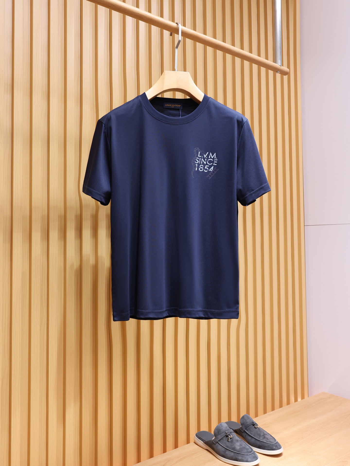 NO:822063,.V Navy Liquid Nitrogen T｜Snake Ladder Lettering Printed Short Sleeves. Made from high-count, high-density long-staple cotton fabrics. After liquid nitrogen cold treatment, the hand feels as smooth and soft as liquid. It has ice-like cooling properties. The upper body is cool but not ice, and it is moisture-wicking and full-bodied. Dark navy navy blue tone, low-key and high-end, not picky on skin tone. The chest adopts the old-style 'L.V.M SINCE'  The 1854' letter print is paired with the brand's iconic snake and ladder elements, and the brand DNA is hidden in the details. The printing uses high-definition offset printing technology, which has strong adhesion, does not crack or fall off, and can keep the texture online even when washed. The old light tone is looming on the dark body, not exaggerated but self-recognizable, which perfectly interprets V's low-key luxury aesthetics. The iconic orange leather label on the back, as a hidden logo of the brand, is low-key and high-end, and the wiring is neat and solid.  The hem adopts double-strand thread + chain thread technology, which is smooth and firm, washable and durable, and has unlimited movement. Same style for men and women, navy blue, XS-XL size; 1-3CM error in flat measurement. XS size: shoulder width 46, chest size 106, dress length 67, sleeve length 22.5. S size: shoulder width 47, chest size 110, dress length 69, sleeve length 23.  L code: Shoulder width 49 Bust 118 Clothes length 73 Sleeve length 24  180-200 pounds choose XL size.,Louis Vuitton-clothing,louis vuitton,T-shirt,19860909.V藏青色液氮T｜灵蛇爬梯字母印花短袖 甄选高支高密长绒棉面料,经过液氮冷处理工艺,手感如液态般丝滑软糯,自带冰感降温属性,上身凉而不冰,吸湿排汗性拉满. 深海军蓝藏青色调,低调高级不挑肤色.胸口采用做旧风格的“L.V.M SINCE 1854”字母印花,搭配品牌标志性的灵蛇与爬梯元素,细节里暗藏品牌DNA. 印花采用高定胶印工艺,附着力强、不开裂、不脱落,水洗也能保持质感在线,做旧的浅色调在深色衣身上若隐若现,不浮夸却自带辨识度,完美诠释了V的低调奢华美学.后背标志性的橙色皮标,作为品牌隐藏标识,低调又高级,走线工整扎实. 下摆采用双股线+锁链线工艺,走线平整牢固,耐洗耐穿,活动不受限. 男女同款,藏青色,XS-XL码； 平铺测量1-3CM误差 XS码:肩宽46胸围106衣长67袖长22.5 S码:肩宽47胸围110衣长69袖长23 M码:肩宽48胸围114衣长71袖长23.5 L码:肩宽49胸围118衣长73袖长24 XL码:肩宽50胸围122衣长75袖长24.5 女生选择XS码； 男生 135斤以下选择XS码；135-150斤选择S码； 150-165斤选择M码；165-180斤选择L码； 180-200斤选择XL码.,路易威登-服装,louis vuitton,T-shirt,,Women's clothing