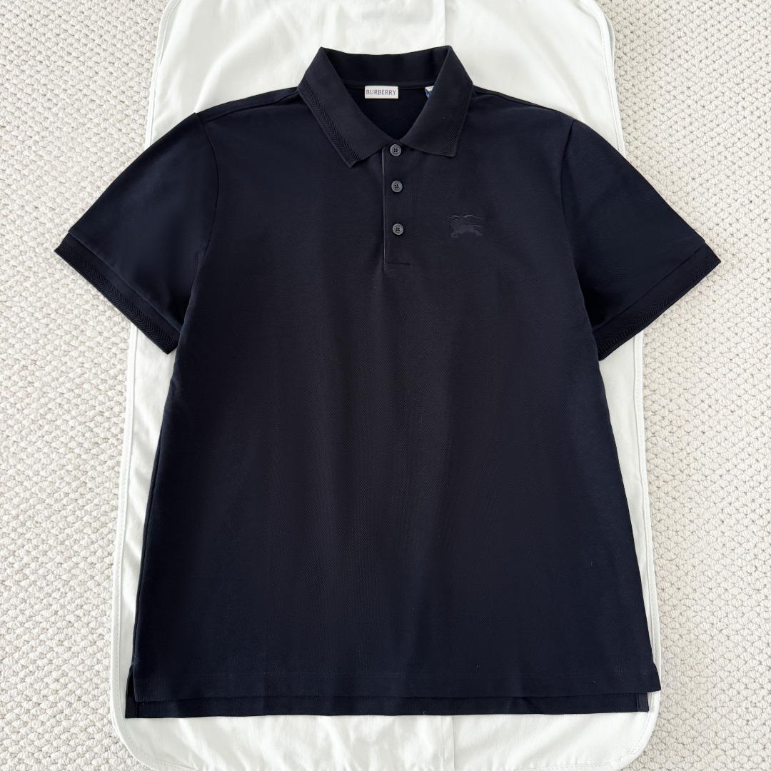 NO:823044,Original 1-1 development navy blue BURBERRY horse embroidered short-sleeved POLO shirt fabric selection  Cotton is selected using pique knitting technology, and a concave and convex mesh texture is formed through a special knitted coil structure. Each group of coils are interlaced with each other to form a breathable 'small honeycomb' structure, forming a pique fabric with a weight of 220g/㎡  , taking into account both stiffness and drape. The pearl mesh structure forms a natural breathable channel, which can quickly discharge moisture from the body surface without causing sweating. At the same time, the pearl texture is delicate and layered, visually matte and low-key, and soft to the touch without sacrificing the muscles.  Embroidery process: Iron the front of the fabric flat in advance, accurately mark the embroidery position, install the embroidery frame into the machine, and align the center point of the pattern. Use high-saturation embroidery thread and pass it through a high-density filling needle. The stitches are fine and even, making the knight and war horse pattern clear and layered, visually embossed and not easy to deform. After finishing, the edges of the pattern are smooth, without hard edges, and there is no foreign body feeling when worn next to the skin. Detail 1  The edge of the neckline is embellished with a densely woven cotton thread of the same color, echoing the texture of the pique cotton fabric, making it visually more refined and tidy. After being set by high-temperature steam, it maintains a perfect lapel shape. It does not curl or collapse after long-term wear and washing. The collar always fits the neck and does not become loose when moving. Detail 2 uses high-transparent resin buttons with a smooth surface and no burrs. The center of the button is engraved with a letter logo, which is high-quality and wear-resistant. Detail 3  The plaid pattern at the placket adopts precise alignment cutting technology to ensure that the plaid lines at the splicing joints are naturally connected and without misalignment. The inner layer uses high-count cotton as the reinforcement layer, combined with the outer plaid fabric, and is shaped after multiple high-temperature presses to ensure that the placket will not roll or warp for a long time, and will always maintain a crisp and neat shape. Accessories One-to-one customized buttons One-to-one customized plaid decoration  SizeSMLXL,Burberry-clothing,burberry,burberry,T-shirt,19860909原版1-1开发 藏青色 BURBERRY巴宝莉战马刺绣短袖POLO衫 面料选择 选用棉采用珠地针织工艺,通过特殊的针织线圈结构形成凹凸的网眼纹理,每一组线圈相互交错,构成透气的“小蜂巢”结构,形成克重达220g/㎡的珠地布,兼顾挺括感与垂坠性.珠地网眼结构形成天然透气通道,能快速导出体表湿气,不闷汗,同时珠地纹理细腻且富有层次,视觉上哑光低调,触感柔软却不失筋骨. 刺绣工艺 将面料前幅,提前熨烫平整,精准标记刺绣位置,将绣花框装入机台,对齐图案中心点.选用高饱和度绣线通过高密度填充针,针脚细密均匀,使骑士与战马图案轮廓清晰,层次分明,视觉上有浮雕感,不易变形.后整理之后,图案边缘平滑,无硬边,贴肤穿着无异物感. 细节1 领口边缘采用同色棉线密织纹理点缀,与珠地棉面料纹理呼应,视觉上更精致整洁.经高温蒸汽定型之后,保持完美翻领形态,久穿、久洗不卷边、不塌陷,活动时领口始终贴合颈部,不松垮 细节2 采用高透树脂纽扣,表面光滑无毛刺,纽扣中心刻有字母标识,质感高级且耐磨. 细节3 门襟处的格纹采用精准对位裁剪工艺,确保拼接处的格纹线条自然衔接、无错位.内层采用高支数棉料作为加固层,配合外层格纹面料,经过多次高温压烫定型,确保门襟长期穿着不翻卷、不起翘,始终保持挺括利落的形态. 辅料一比一定制纽扣  一比一定制门襟格纹装饰 SizeSMLXL,博柏利-服装,burberry,burberry,T-shirt,,Women's clothing