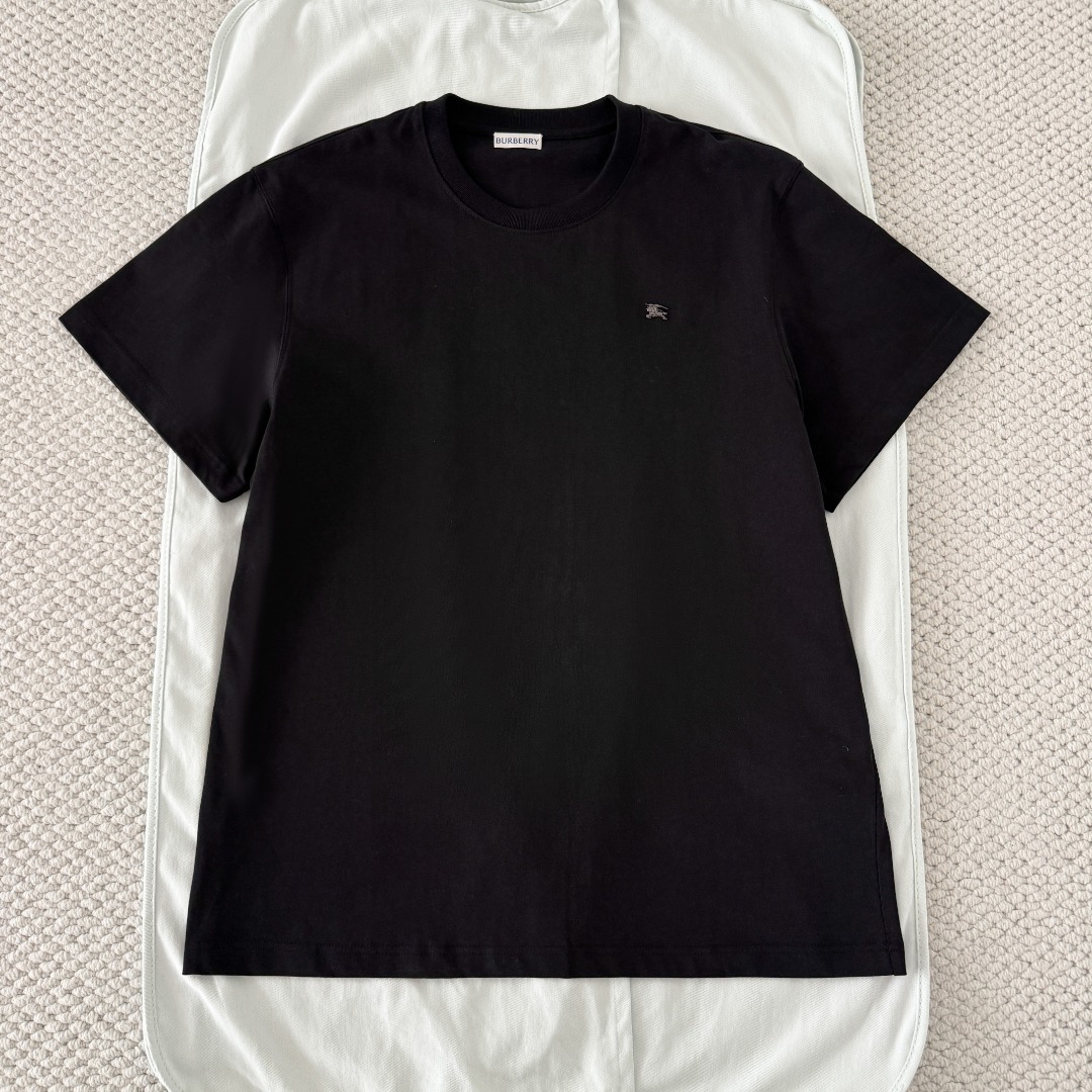 NO:823021,Original 1-1 development BURBERRY/metallic equestrian logo cotton short-sleeved T-shirt fabric selection  We select 220GSM combed jersey cotton, with just the right thickness. The fabric surface is smooth and delicate, with soft and stiffness, and the upper body is neat and not soft; the natural cotton feels skin-friendly and breathable, moisture-wicking and non-sticky, making it refreshing and comfortable for daily wear. The structural texture is fine and even, with a clear knitted coil texture on the front. It also has moderate elasticity, no restrictions on movement, and is not easy to loose, deform, snag or wrinkle after repeated machine washing, taking into account both texture and durability.  Details: The logo adopts an integrated die-casting process. The knight's posture and the horse's lines are presented in three-dimensional relief. The edges have been polished and trimmed many times without burrs or sharp edges, forming a finished product with clear outlines and distinct layers of details. You can feel the obvious concave and convex texture when you touch it, rather than the thin effect of flat printing. Riveting process  In order to ensure that each logo accurately falls at the preset position, laser positioning technology is first used to mark the fixed position of each front panel. Then the rivets at the bottom of the logo are riveted to the negative film through equipment. A soft rubber gasket is installed on the back of the logo to prevent the metal logo from directly rubbing the fabric, causing snags and wear, and extending the service life of the fabric. The rivets form a strong fixed point after penetrating the fabric. The tensile force test can reach more than 5kg, and they will not easily loosen and fall off after machine washing and rubbing. Auxiliary materials One-to-one customization of metal logos One-to-one customization of three standards  SizeSMLXL,Burberry-clothing,burberry,burberry,T-shirt,tees,t-shirt,19860909原版1-1开发 BURBERRY巴宝莉/金属马术徽标棉质短袖T恤 面料选择 甄选220GSM精梳平纹针织棉,厚度恰到好处,布面光洁细腻,自带柔和挺括度,上身利落不软塌；天然棉感亲肤透气,吸湿排汗不黏腻,日常穿着清爽舒适.结构纹理细腻均匀,正面呈现清晰的针织线圈肌理,同时自带适中弹力的特性,活动无束缚,反复机洗也不易松垮变形、勾丝起皱,兼顾质感与耐用性. 细节 徽标采用一体压铸成型工艺,骑士的姿态、马匹的线条都以立体浮雕形式呈现,边缘经过多次抛光修边,无毛刺、无尖锐棱角,形成轮廓清晰利落的成品,细节层次分明,触摸时能感受到明显的凹凸质感,而非平面印刷的单薄效果. 铆合工艺 为确保每一枚徽标都精准落在预设位置,先采用激光定位技术在每一片前幅固定位子做标记.再通过设备将徽标底部的铆钉与底片铆合,徽标背面会加装软胶垫片,防止金属徽标直接摩擦面料导致勾丝、磨损,延长面料使用寿命,铆钉穿透面料后形成牢固的固定点,拉力测试可达5kg以上,机洗揉搓都不会轻易松动脱落. 辅料一比一定制金属徽标  一比一定制三标 SizeSMLXL,博柏利-服装,burberry,burberry,T-shirt,tees，t-shirt,,Women's clothing
