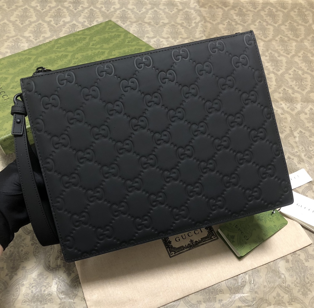 一款以黑色橡胶效果皮革打造的男士手拿包闪亮登场，全新材质为这款设有一个腕带提手的时尚单品带来视觉上的全新