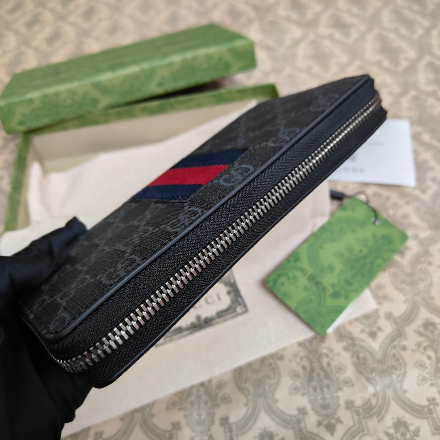由Gucci最具辨识性的两种标志 — GG图案和织带精心搭配制作。此款全拉链式钱包采用GG Suprem