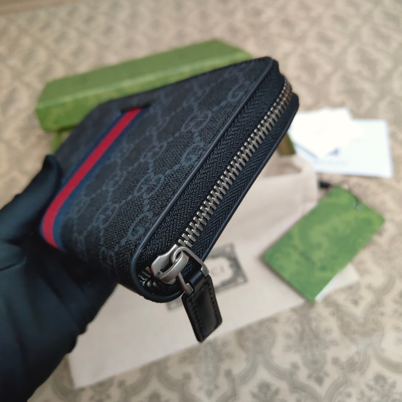 由Gucci最具辨识性的两种标志 — GG图案和织带精心搭配制作。此款全拉链式钱包采用GG Suprem