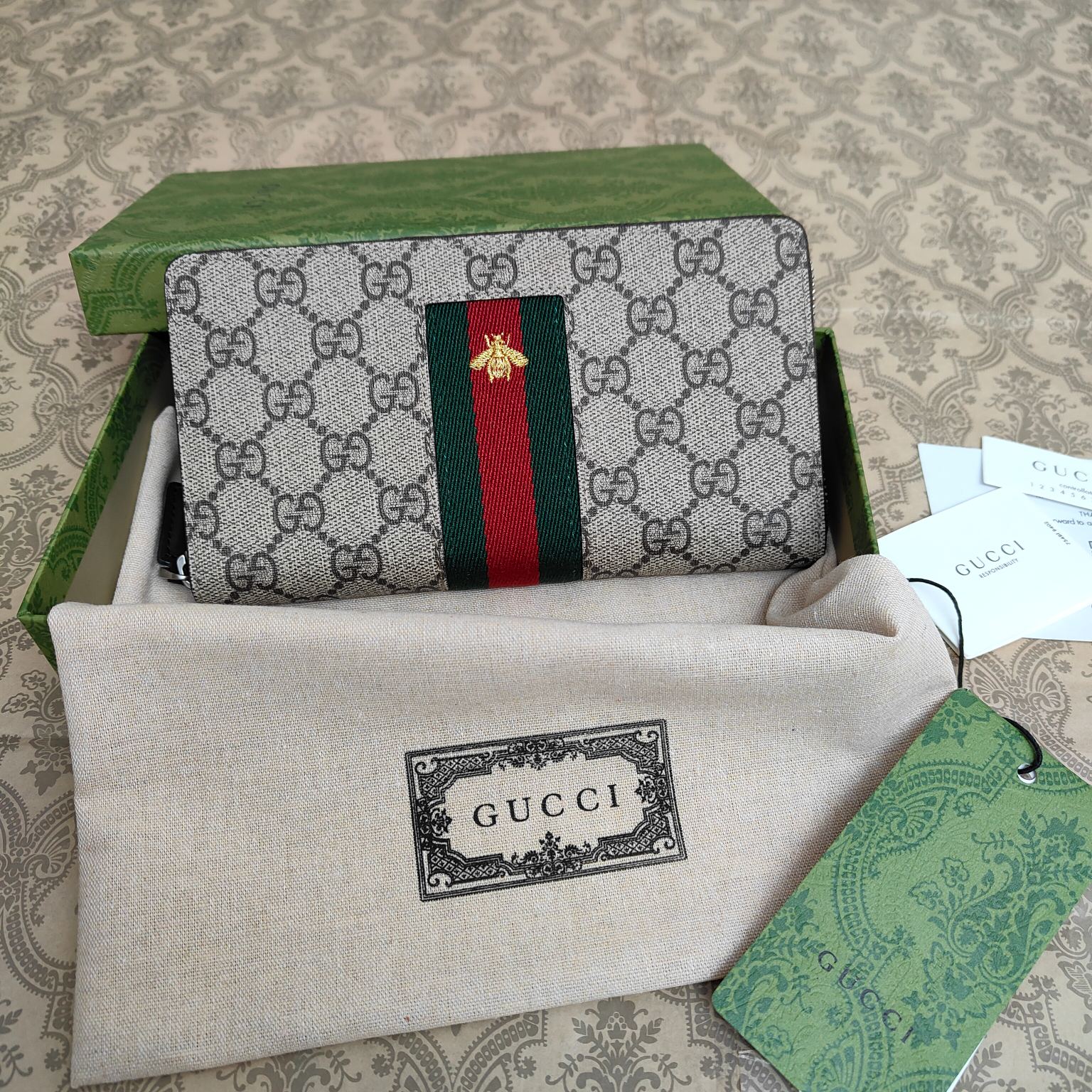 由Gucci最具辨识性的两种标志 — GG图案和织带精心搭配制作。此款全拉链式钱包采用GG Suprem