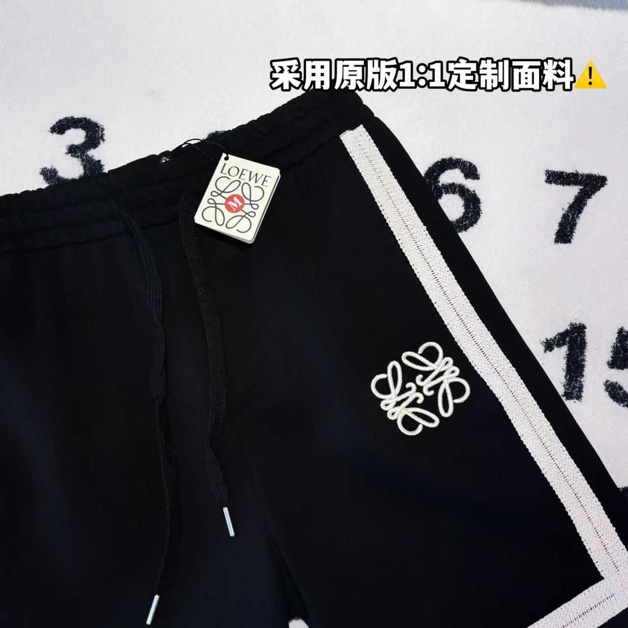 發75💰

-LOEWE罗意威刺绣拼接色织织带短裤 男女同款

-面料：采用原版一比一面料。

-辅料：原版拆解开发，一比一定制的小标，领标，水洗，吊牌，五金等等。

-工艺：原版分解，从裁剪，拼接，到缝制工艺完全原版一比一。

-颜色：黑色

-尺码：S M L XL
      裤长     腰围     臀围     推荐尺码
S     58       76        108      120斤内
M   59       80         112      140斤内
L     60       84         116      160斤内
XL   61       88         120      190斤内   