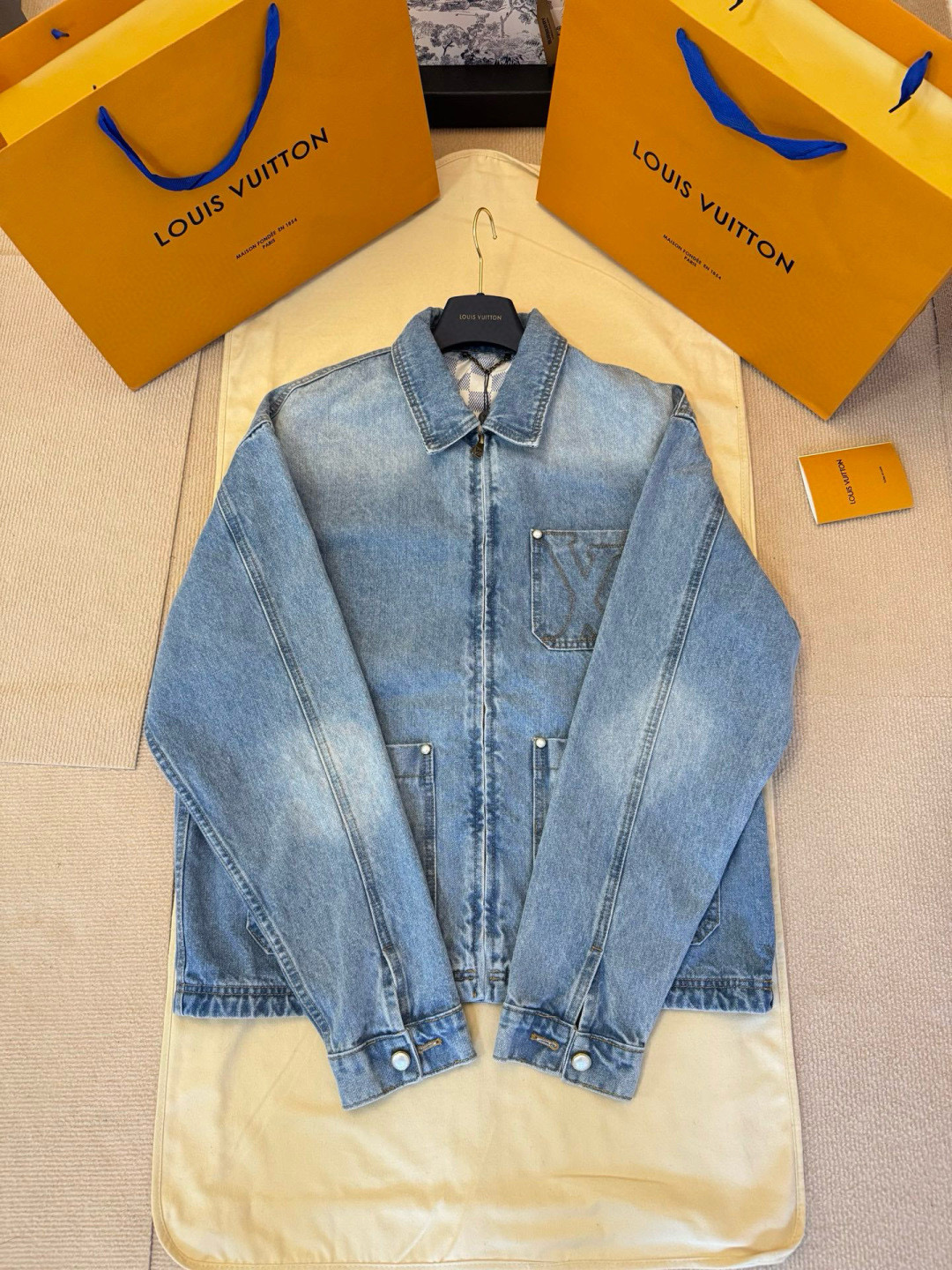 NO:638464,Exclusive original development of LOUIS VUITTON pocket embroidered workwear denim jacket  Process description: Made of cotton fabric, a slight distressed effect is created through fine washing process, providing a lightweight option for warmer seasons. The jacket's LV embroidered chest pocket and rear nubuck LV patch show the brand's attention to detail. The embellishment of pearl buttons and rivets adds to the Dandy style  The jacket's hidden zipper front and pearlescent buttons on the cuffs are equipped with distressed bottoms, and the logo embroidery on the chest patch pocket highlights the brand's classics and innovation. The yoke part is equipped with Damier lining, and the overall design is both fashionable and practical, perfectly integrating traditional craftsmanship and modern aesthetics.  Color blue Size46/48/50/52,Louis Vuitton-clothing,louis vuitton,louis vuitton,louis vuitton,jackets & coats,jackets & coats,alexander wang19860909独家原版开发LOUIS VUITTON口袋刺绣工装牛仔外套 工艺说明采用棉质面料,通过精细的水洗工艺营造出轻微做旧效果,为温暖时节提供轻盈选择.夹克的LV刺绣胸袋和后部正绒面革LV贴饰展现了品牌对细节的考究.珠光纽扣和铆钉的点缀,增添了丹迪风格的优雅.夹克的隐藏式拉链前襟和袖口珠光纽扣,均配有做旧底,胸前贴袋上的标识刺绣,彰显了品牌的经典与创新.育克部分配有Damier内衬,整体设计既时尚又实用,完美融合了传统工艺与现代审美. 颜色蓝色 Size46/48/50/52,路易威登-服装,louis vuitton,louis vuitton,louis vuitton,jackets & coats,jackets & coats,alexander wang,Women's clothing