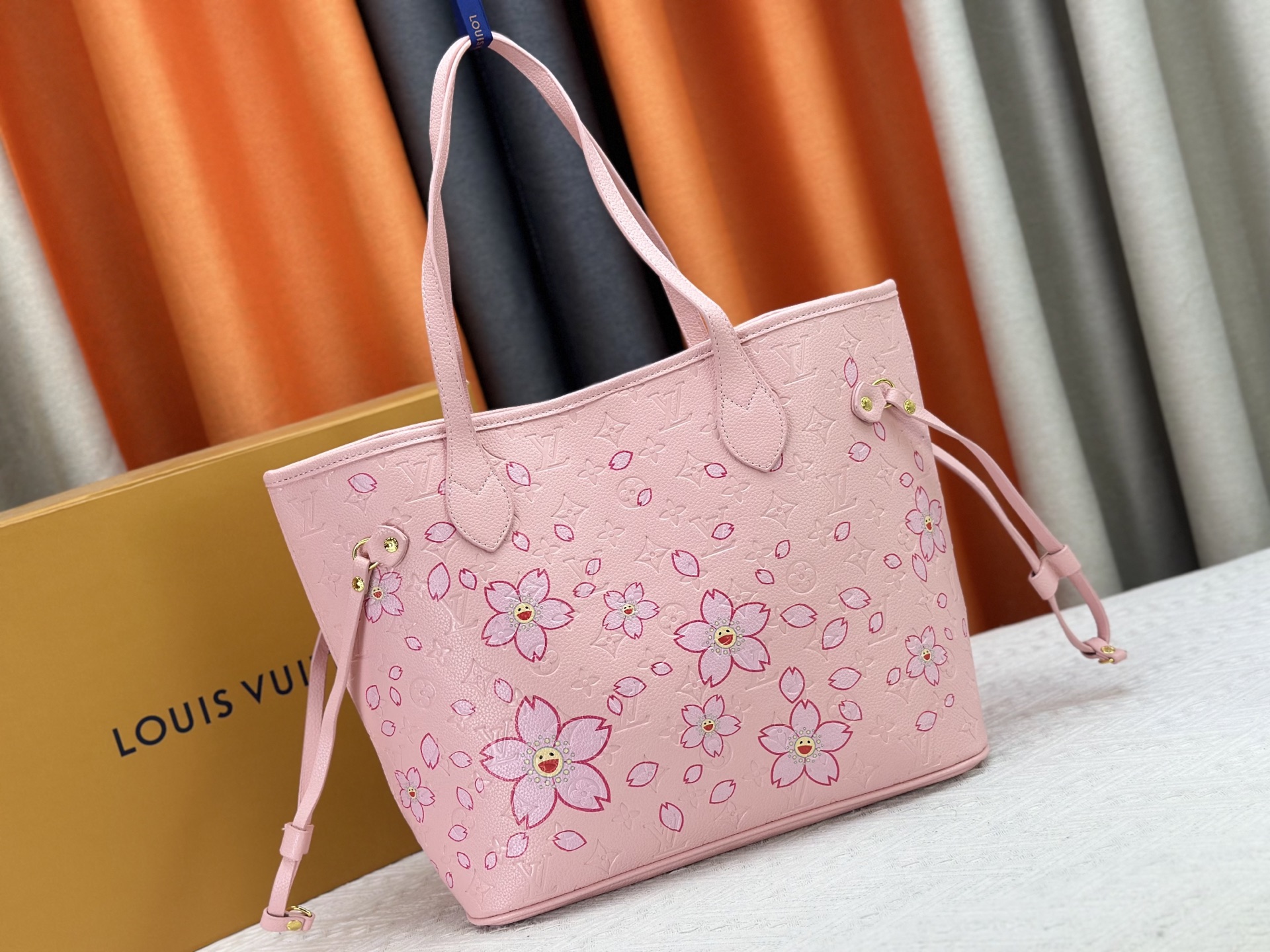 P170 M40995 M17088村上隆 粉色樱花🌸极具传奇色彩的Neverfull中号手袋： 总是能够满足您对手提包的各种需要。 容量大却不显笨重，挺括而手感柔软，居家出行皆宜。 束紧侧边系带，立刻变身为一款时尚的都市手袋。 松开系带，又变成一款别致而实用的手提包。 细长的皮革手柄既宜肩背，亦可挽拎于臂间。 此处显示的此款以 Damier Azur 帆布制成。
尺寸： 31x28x14cm