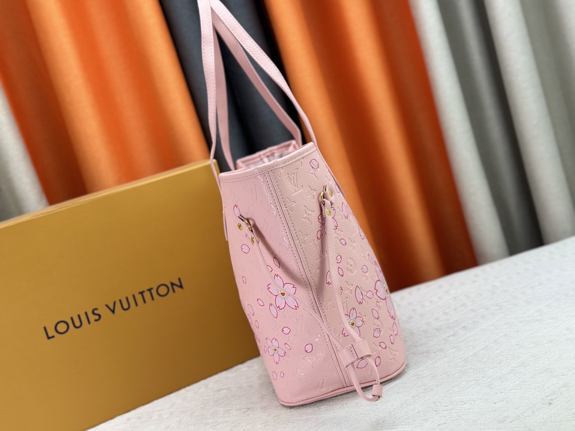 P170 M40995 M17088村上隆 粉色樱花🌸极具传奇色彩的Neverfull中号手袋： 总是能够满足您对手提包的各种需要。 容量大却不显笨重，挺括而手感柔软，居家出行皆宜。 束紧侧边系带，立刻变身为一款时尚的都市手袋。 松开系带，又变成一款别致而实用的手提包。 细长的皮革手柄既宜肩背，亦可挽拎于臂间。 此处显示的此款以 Damier Azur 帆布制成。
尺寸： 31x28x14cm