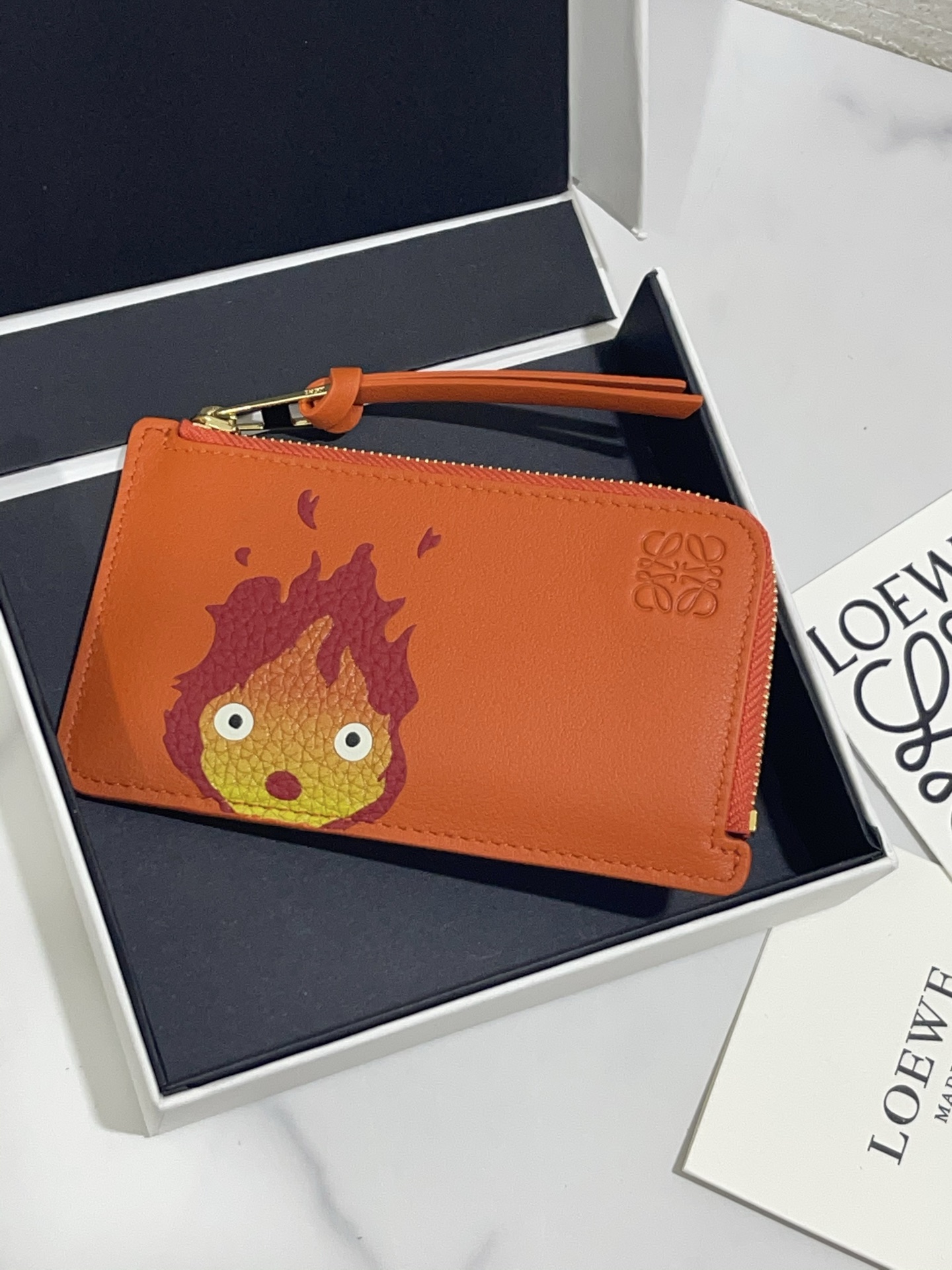 NO:813521,Calcifer Zippered Card Holder Howl's Moving Castle is said to be the final work of Hayao Miyazaki. It is made of classic calfskin, using precise cutting technology and inlay technology. It has 4 card slots and a large zippered pocket. The model size is 13*7.5, (note that since the pattern is hand-inlaid and spliced, it is normal for there to be gaps and leather flakes), Loewe wallet, loewe, wallets, cowhide19860909Calcifer 拉链卡包哈尔的移动城堡  据说是与宫崎骏的收官之作  选用经典小牛皮制作,采用精确的切割技术,以镶嵌工艺制成,4 个卡位和一个袋拉链的大口袋.款号尺寸13*7.5,（注意 由于图案是手工镶嵌拼接的, 有缝隙、 皮料有皮屑属于正常现象）,罗意威钱包,loewe,wallets,cowhide,Wallet purse