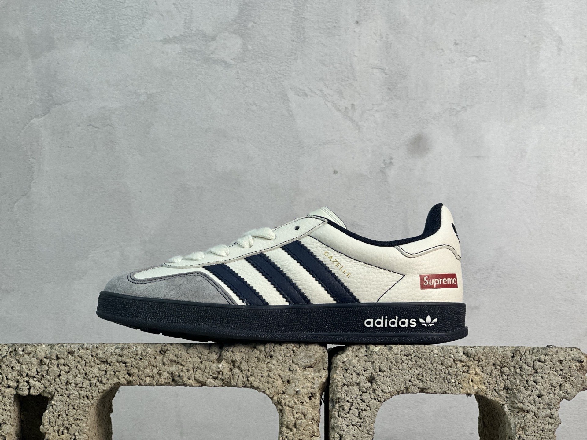 本地150💰放店私 adidas originals GAZELLE INDOOR Indoor LV T头鞋 SUP联名 防滑耐磨轻便 低帮 板鞋 男女同款 米白藏蓝
以柔软的皮革鞋面搭配耐磨橡胶外底，展现出复古与现代的融合。鞋面采用细腻纹理设计，搭配三条杠，尽显品牌经典。无论是运动场还是街头，这双鞋都能轻松驾驭。
货号:DM1234-003
尺码:36 36.5 37 38 38.5 39 40 40.5 41 42 42.5 43 44 44.5 45