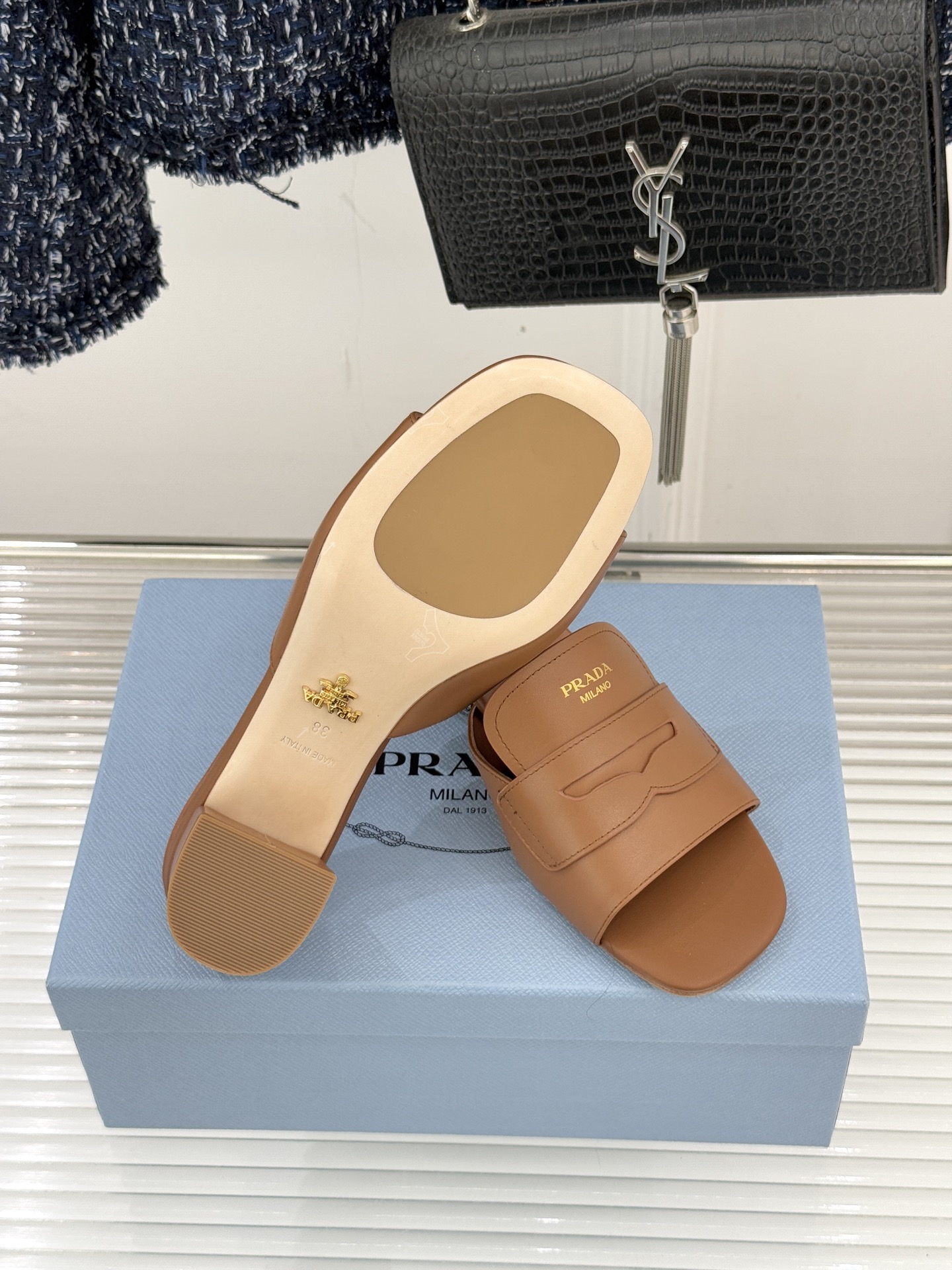 Prada/普拉达经典极简字母粗跟拖鞋循“基调之变”的设计哲思这双跟拖鞋解构奢华本质。以利落线条勾勒锥形