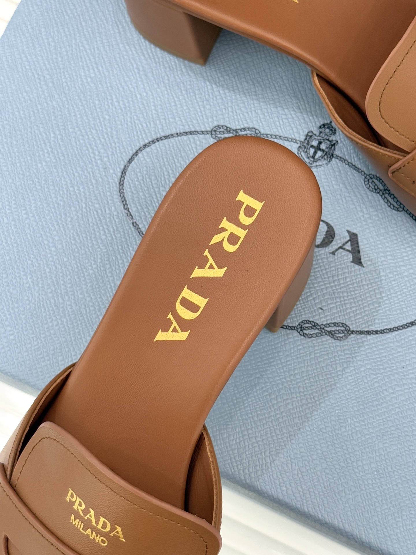 Prada/普拉达经典极简字母粗跟拖鞋循“基调之变”的设计哲思这双跟拖鞋解构奢华本质。以利落线条勾勒锥形