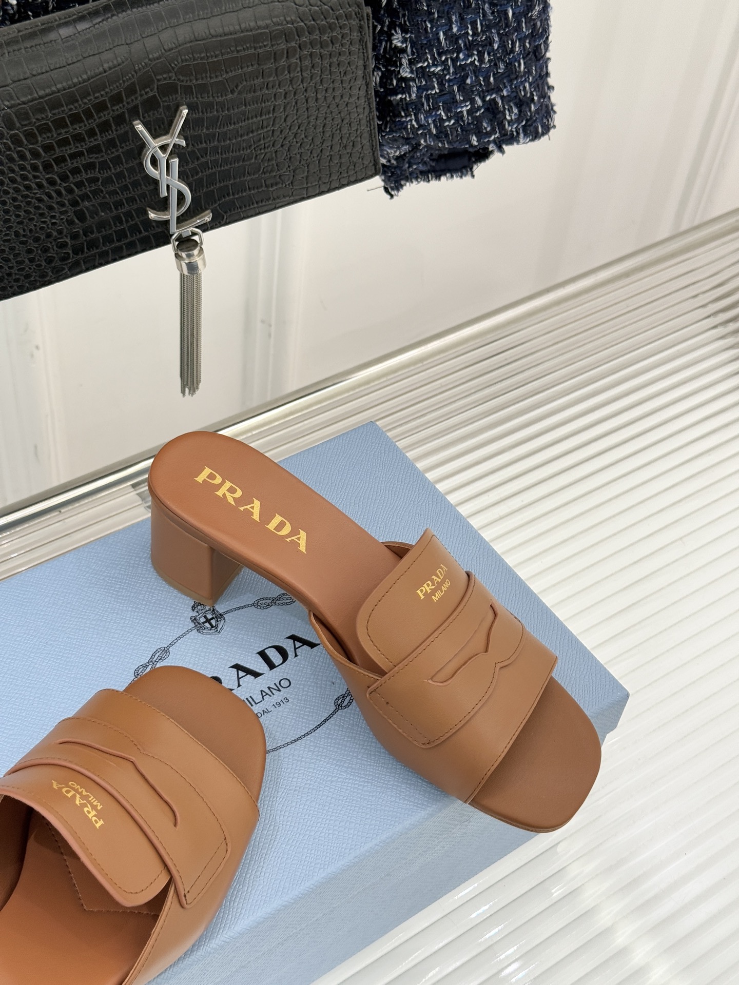 Prada/普拉达经典极简字母粗跟拖鞋循“基调之变”的设计哲思这双跟拖鞋解构奢华本质。以利落线条勾勒锥形