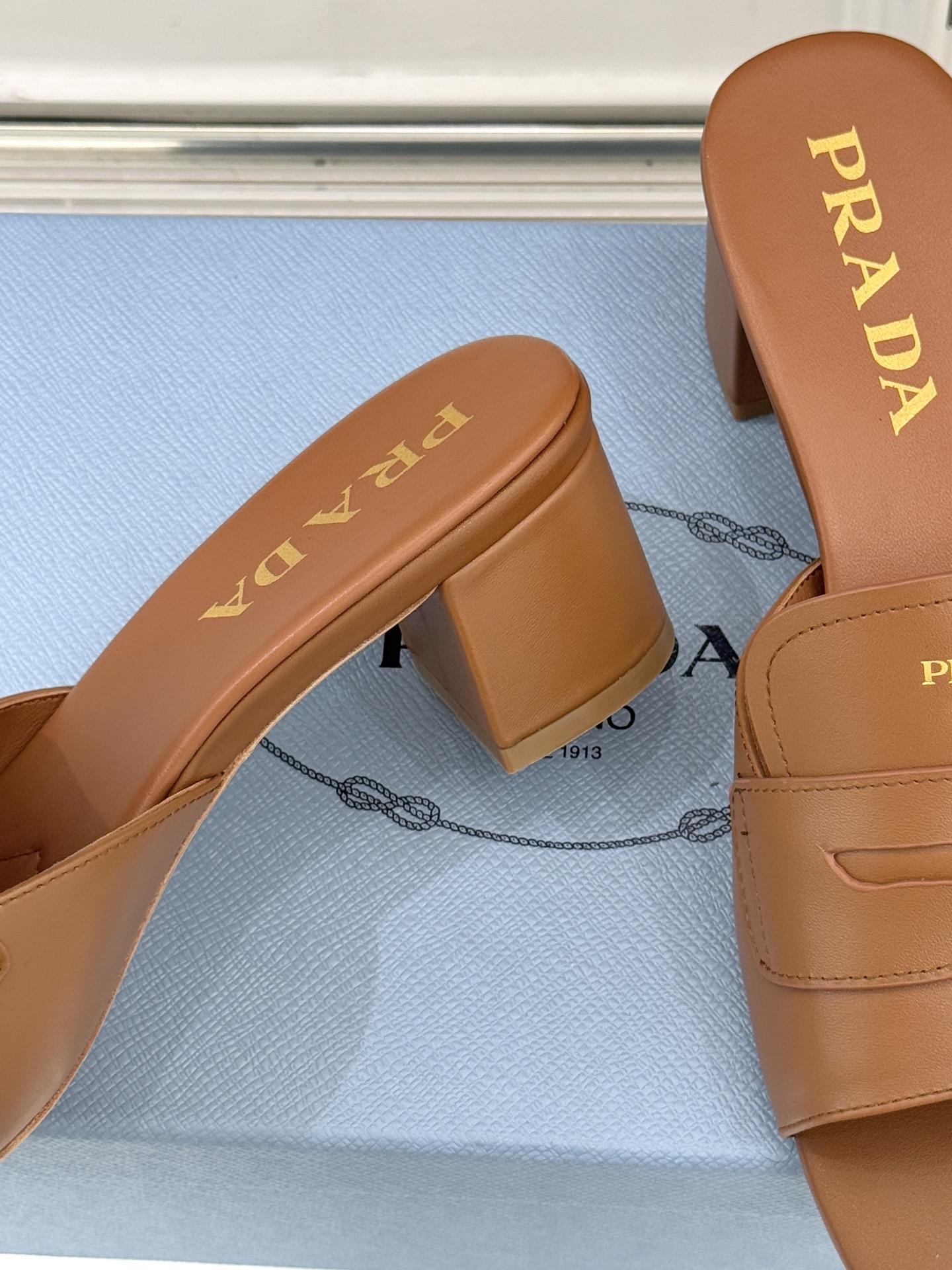 Prada/普拉达经典极简字母粗跟拖鞋循“基调之变”的设计哲思这双跟拖鞋解构奢华本质。以利落线条勾勒锥形