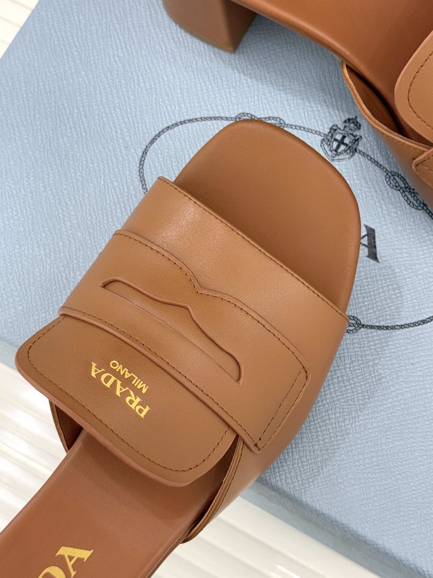 Prada/普拉达经典极简字母粗跟拖鞋循“基调之变”的设计哲思这双跟拖鞋解构奢华本质。以利落线条勾勒锥形