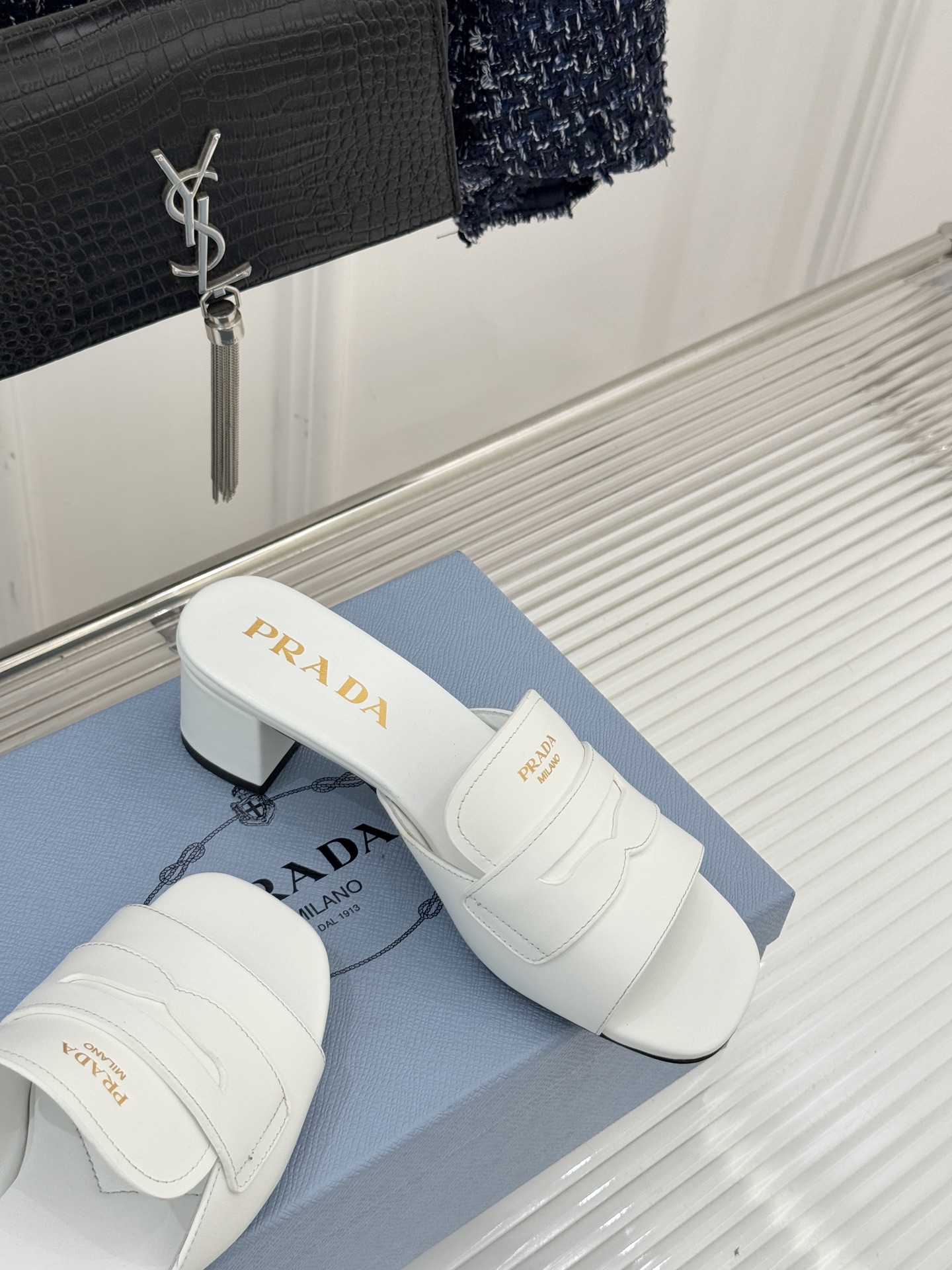 Prada/普拉达经典极简字母粗跟拖鞋循“基调之变”的设计哲思这双跟拖鞋解构奢华本质。以利落线条勾勒锥形