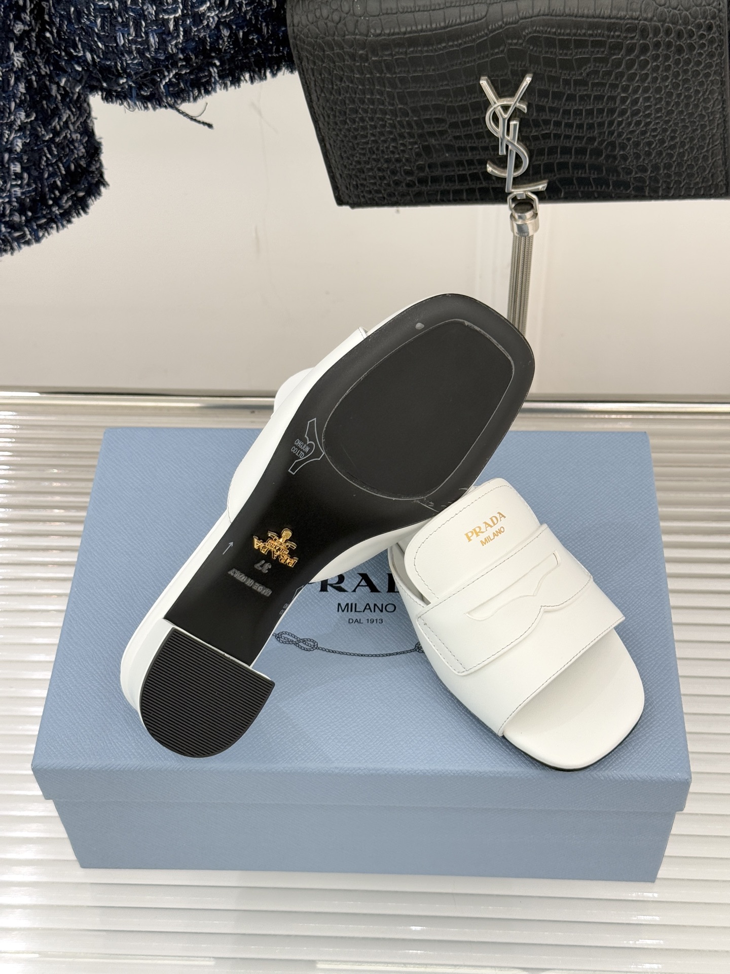 Prada/普拉达经典极简字母粗跟拖鞋循“基调之变”的设计哲思这双跟拖鞋解构奢华本质。以利落线条勾勒锥形