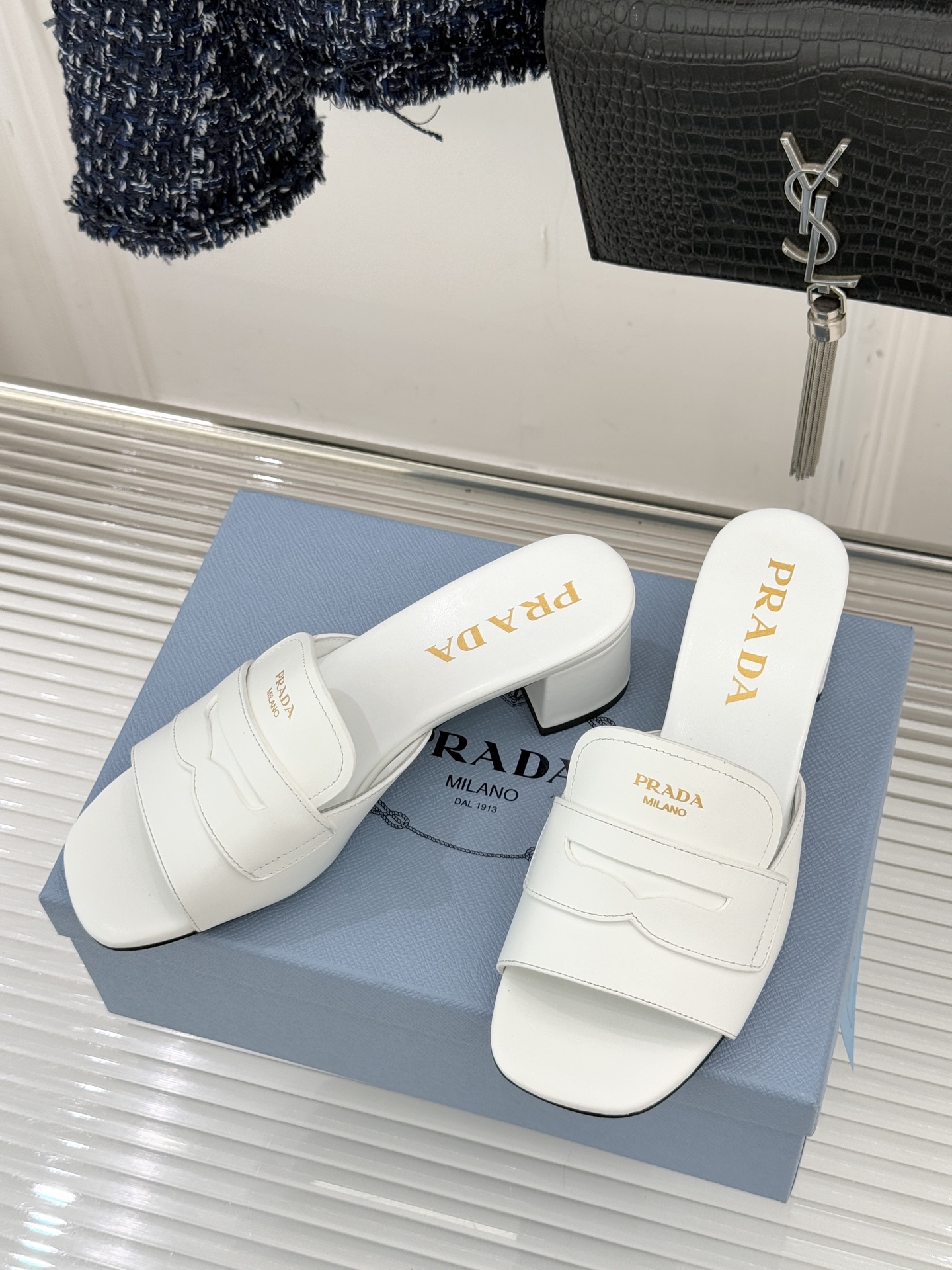 Prada/普拉达经典极简字母粗跟拖鞋循“基调之变”的设计哲思这双跟拖鞋解构奢华本质。以利落线条勾勒锥形