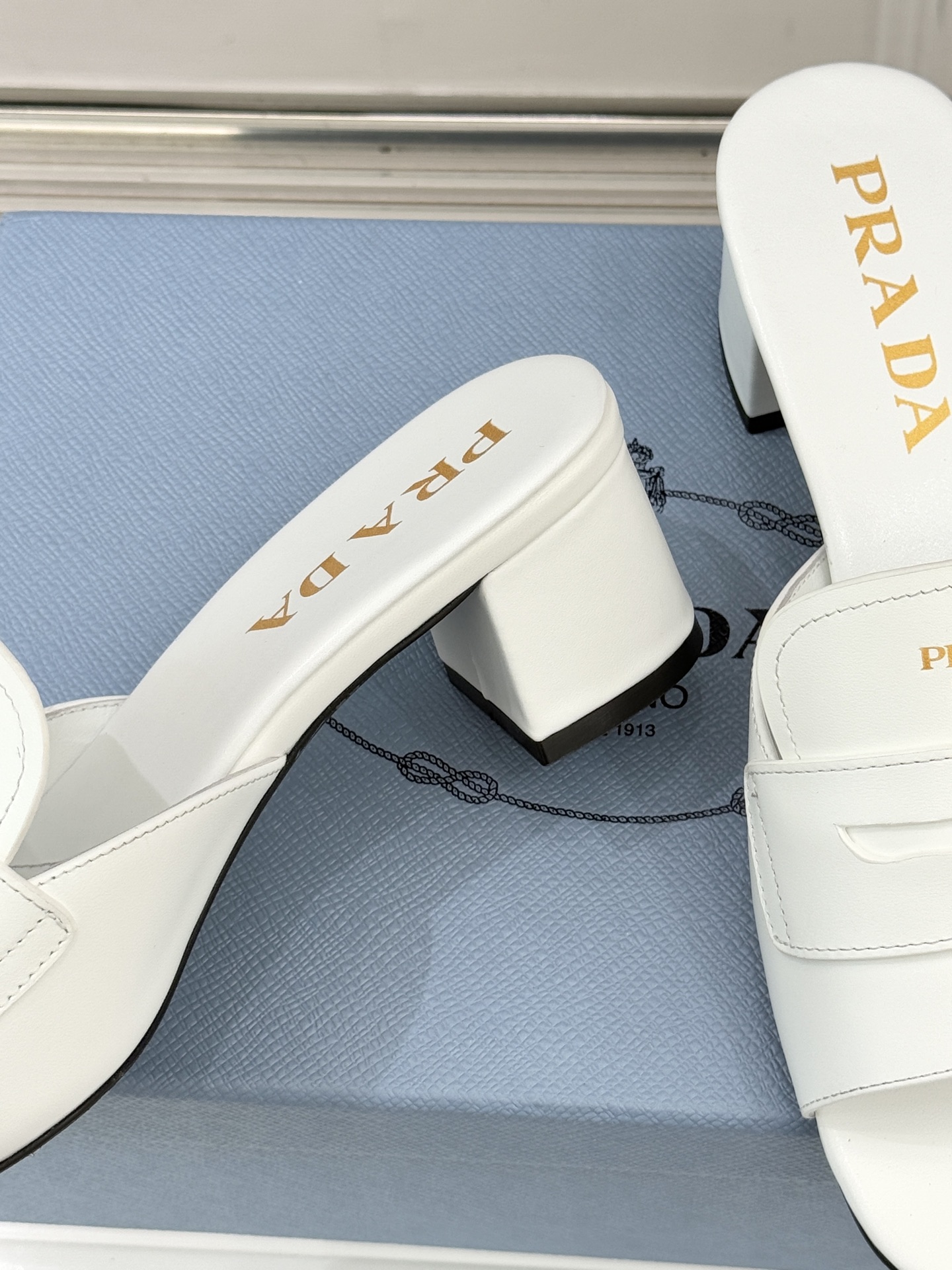 Prada/普拉达经典极简字母粗跟拖鞋循“基调之变”的设计哲思这双跟拖鞋解构奢华本质。以利落线条勾勒锥形