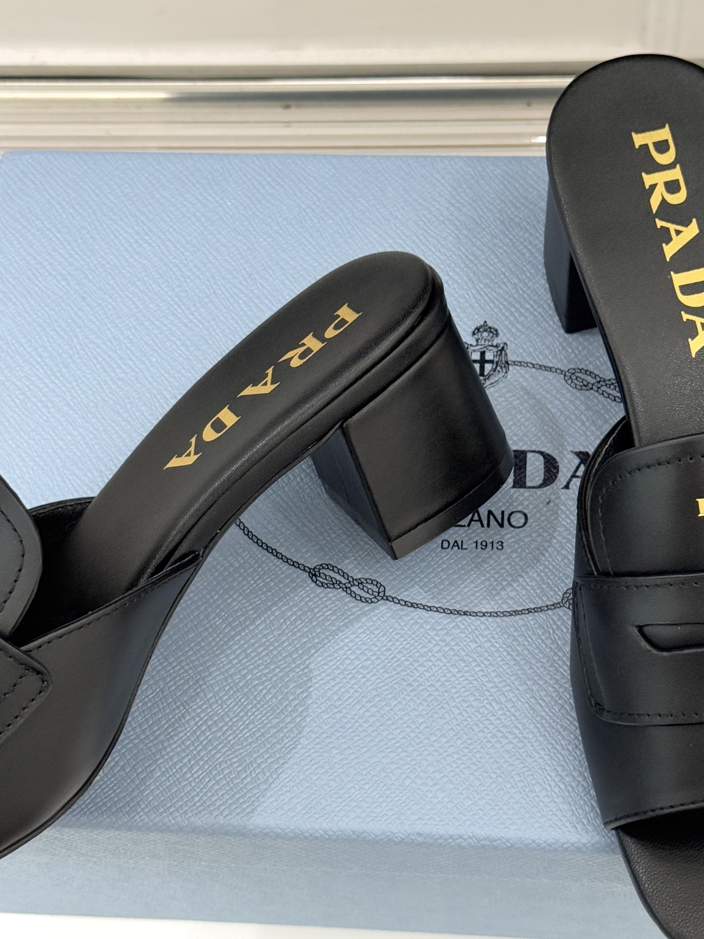 Prada/普拉达经典极简字母粗跟拖鞋循“基调之变”的设计哲思这双跟拖鞋解构奢华本质。以利落线条勾勒锥形