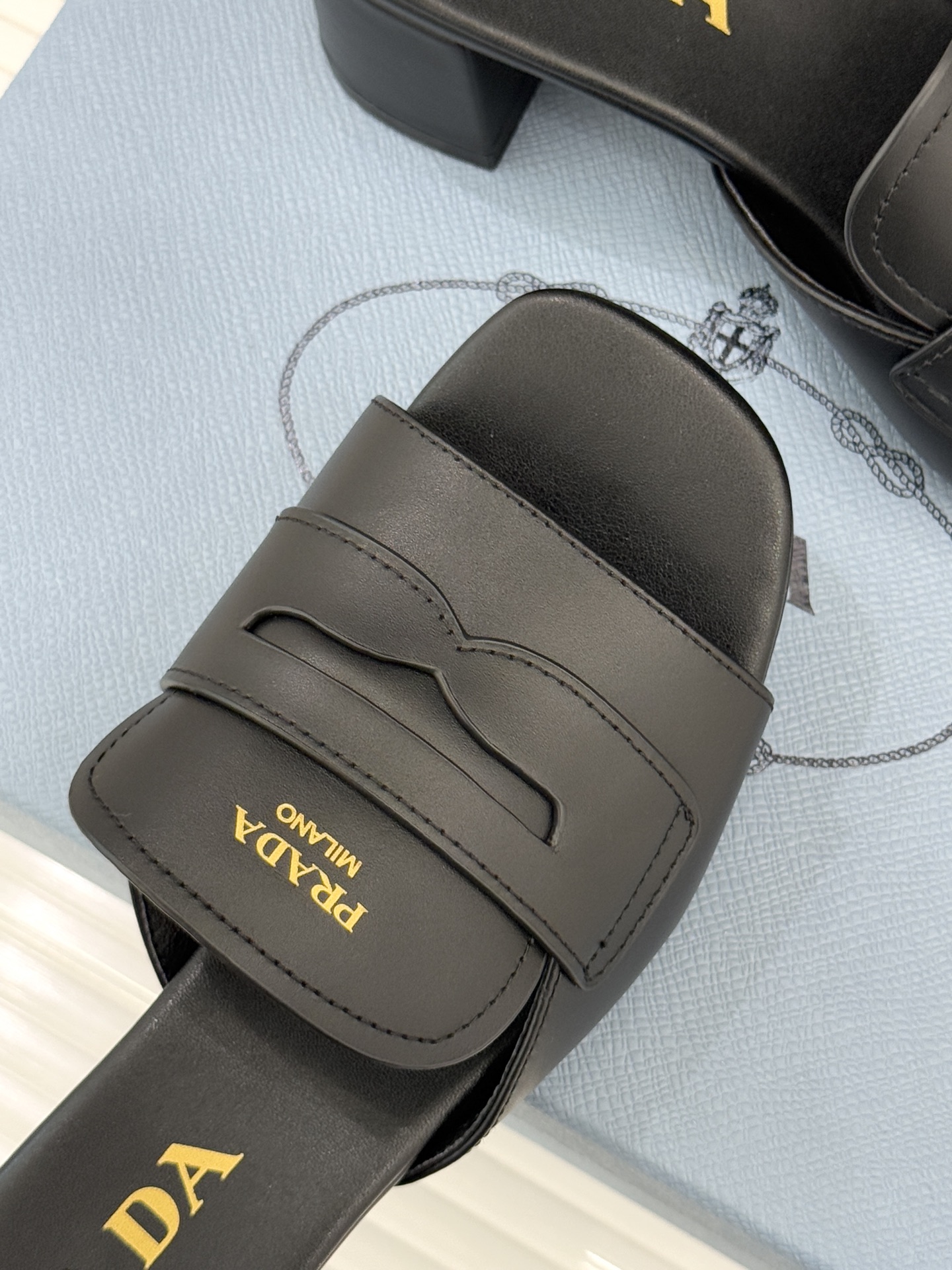 Prada/普拉达经典极简字母粗跟拖鞋循“基调之变”的设计哲思这双跟拖鞋解构奢华本质。以利落线条勾勒锥形