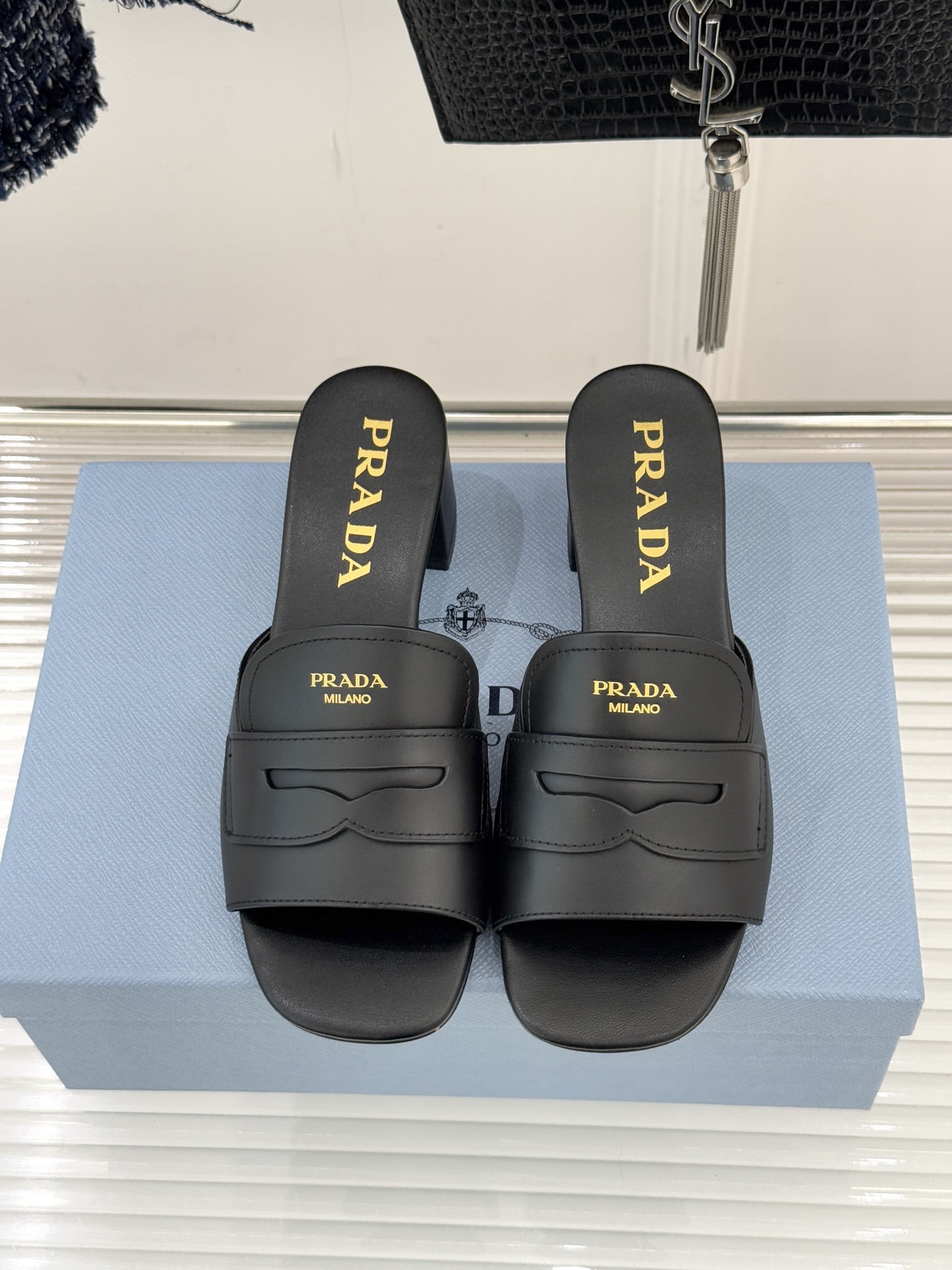 Prada/普拉达经典极简字母粗跟拖鞋循“基调之变”的设计哲思这双跟拖鞋解构奢华本质。以利落线条勾勒锥形