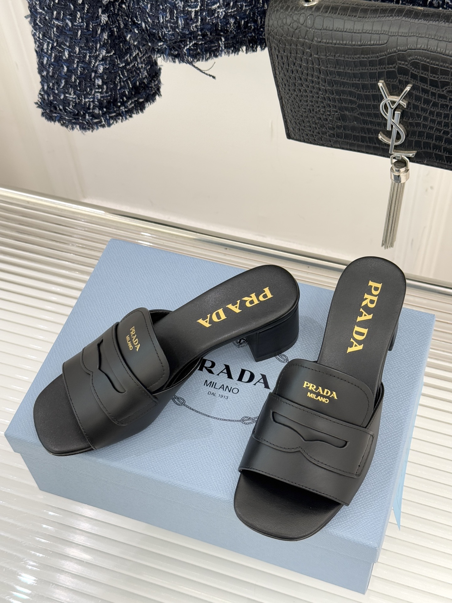 Prada/普拉达经典极简字母粗跟拖鞋循“基调之变”的设计哲思这双跟拖鞋解构奢华本质。以利落线条勾勒锥形
