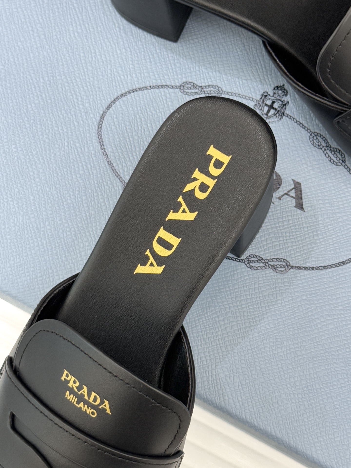 Prada/普拉达经典极简字母粗跟拖鞋循“基调之变”的设计哲思这双跟拖鞋解构奢华本质。以利落线条勾勒锥形